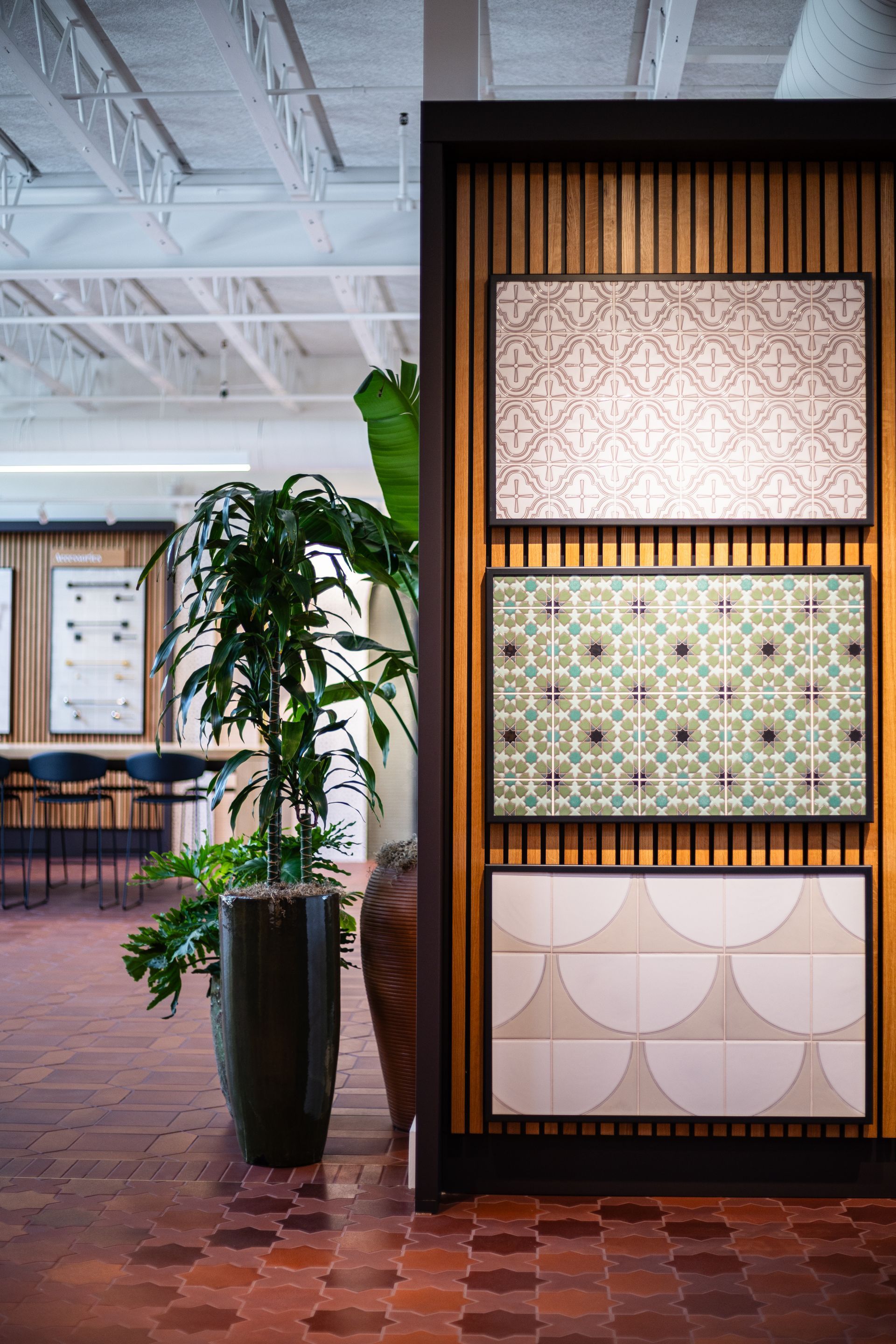 Indoor office lobby with decorative tile display and a tall potted plant on a red brick floor