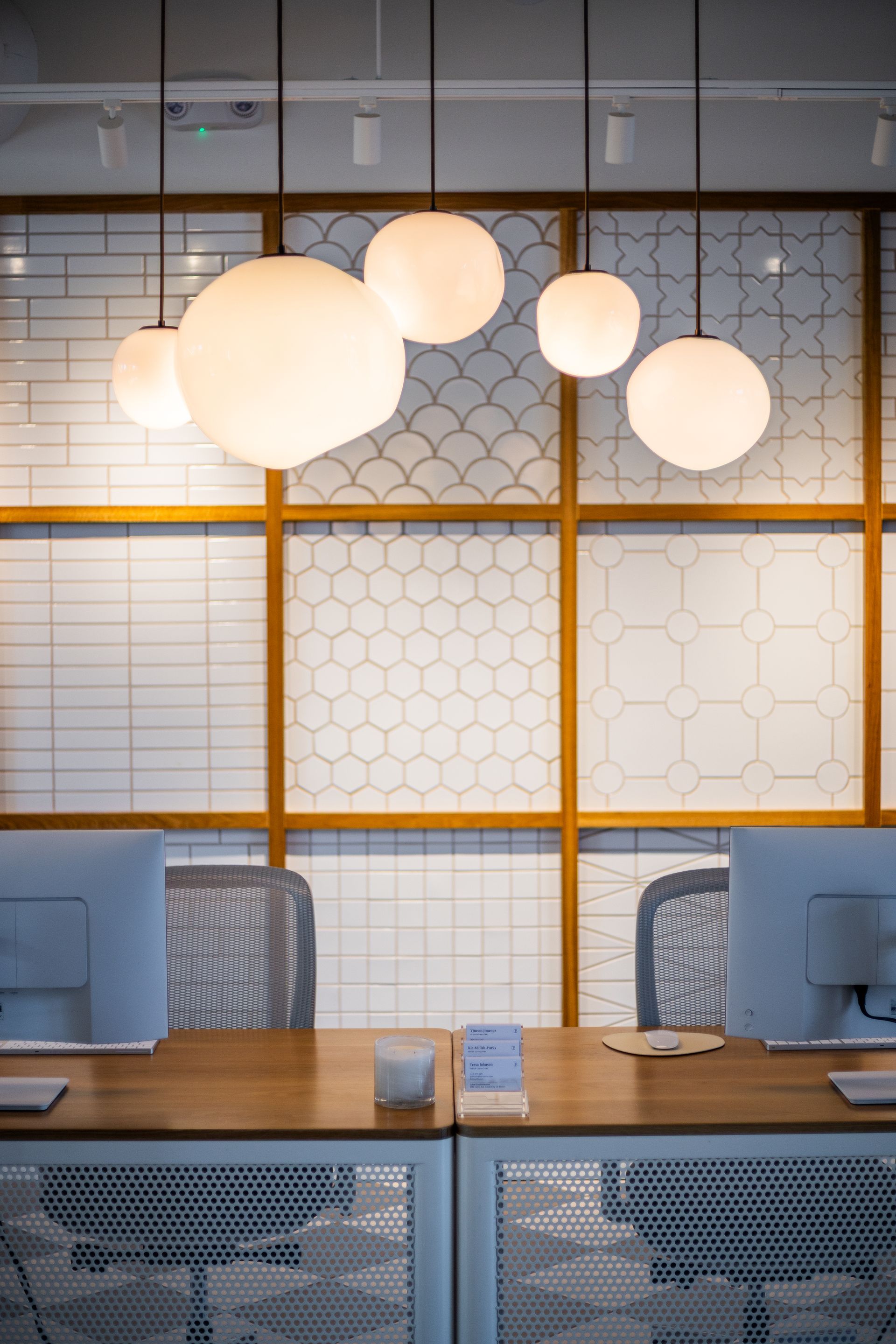 Modern café interior with hanging globe lights, wooden table, and blue patterned chairs