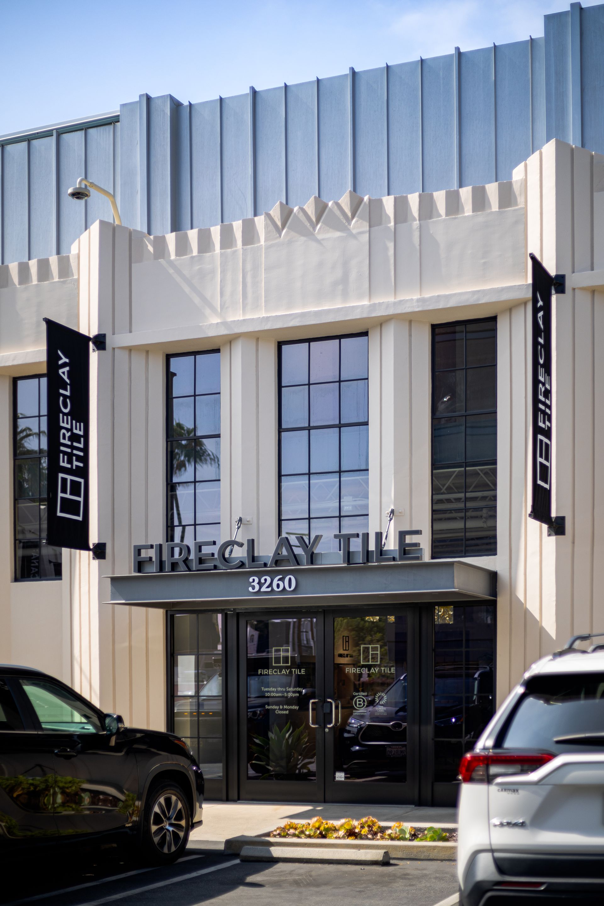 Fireclay Tile storefront with tall cream facade and black signage, viewed from the parking lot