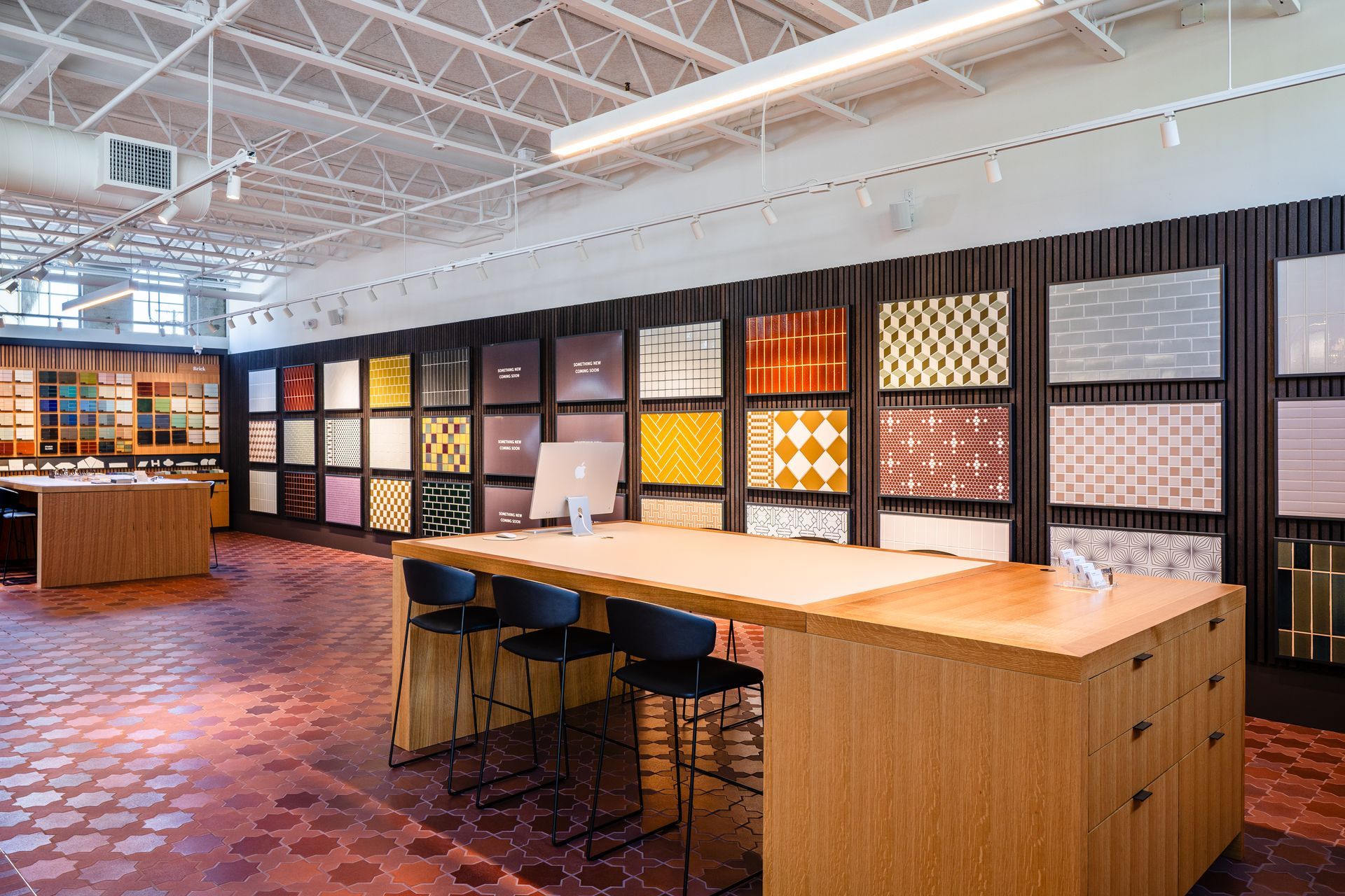 Modern office showroom with wood tables, sample wall displays, and a patterned tile floor