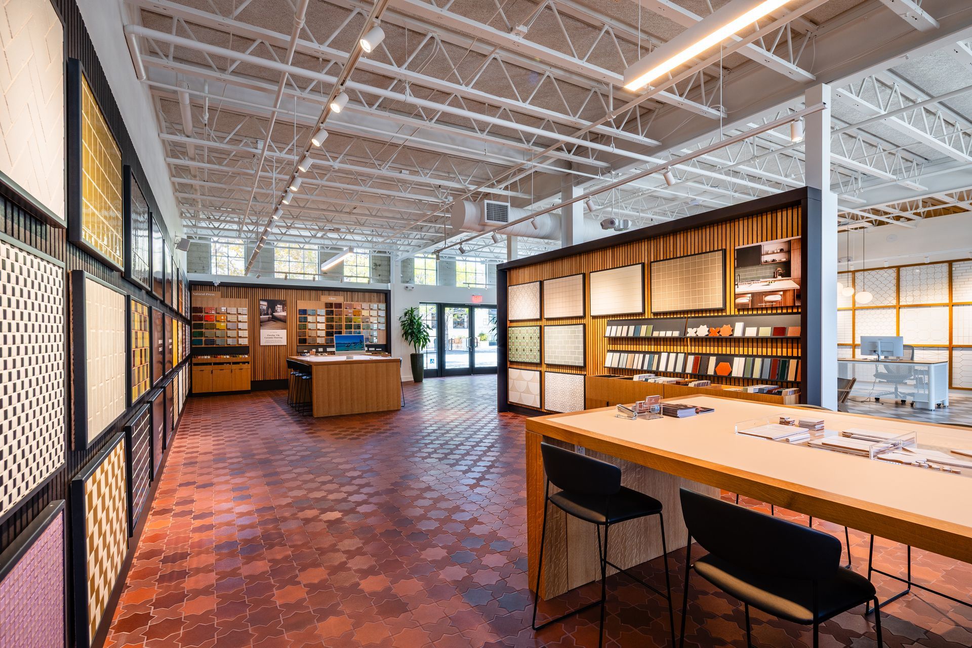 Modern library interior with bookshelves, wooden tables, and a brick floor under a bright open ceiling