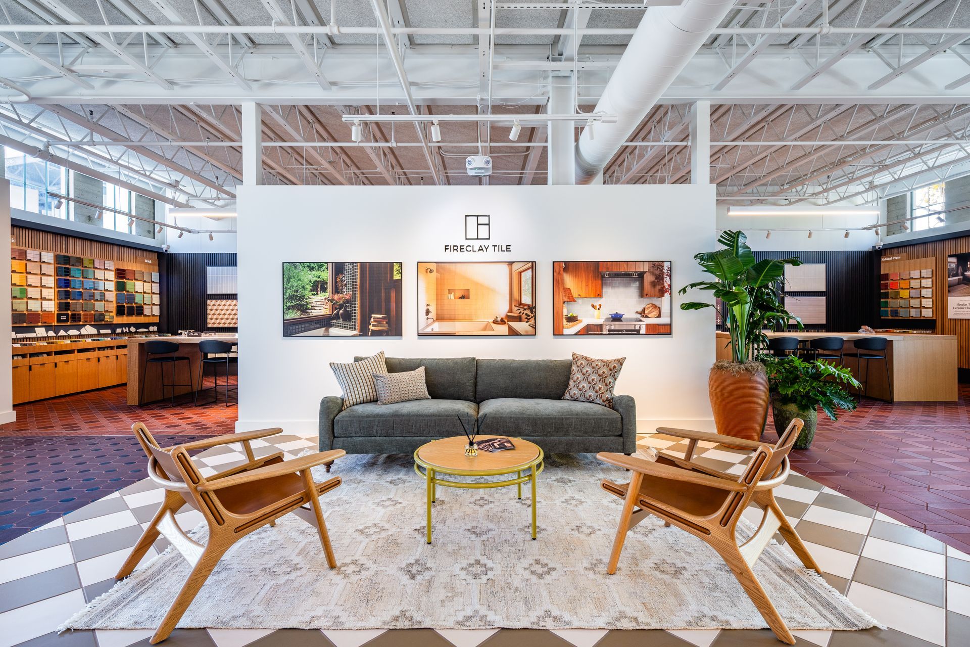 Modern showroom lounge with gray sofa, wooden chairs, patterned rug, and open shelving displays