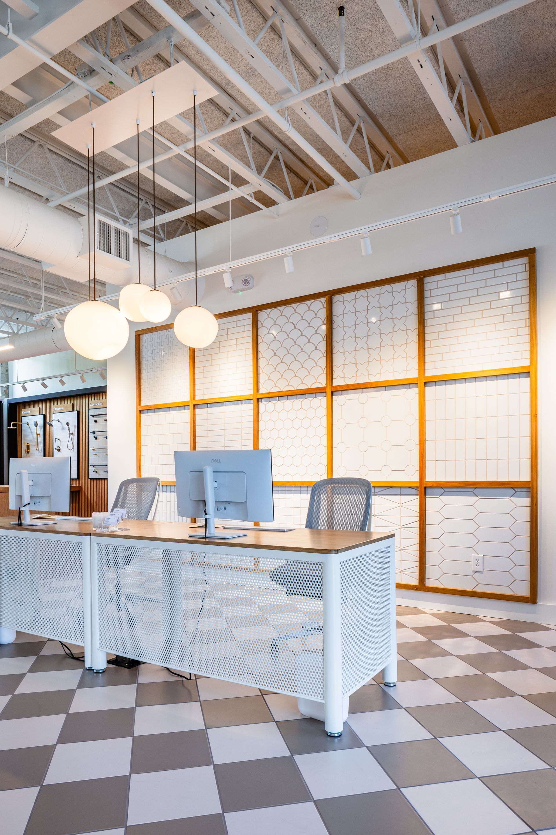 Modern reception desk in a bright office with white pendant lights and orange-framed windows