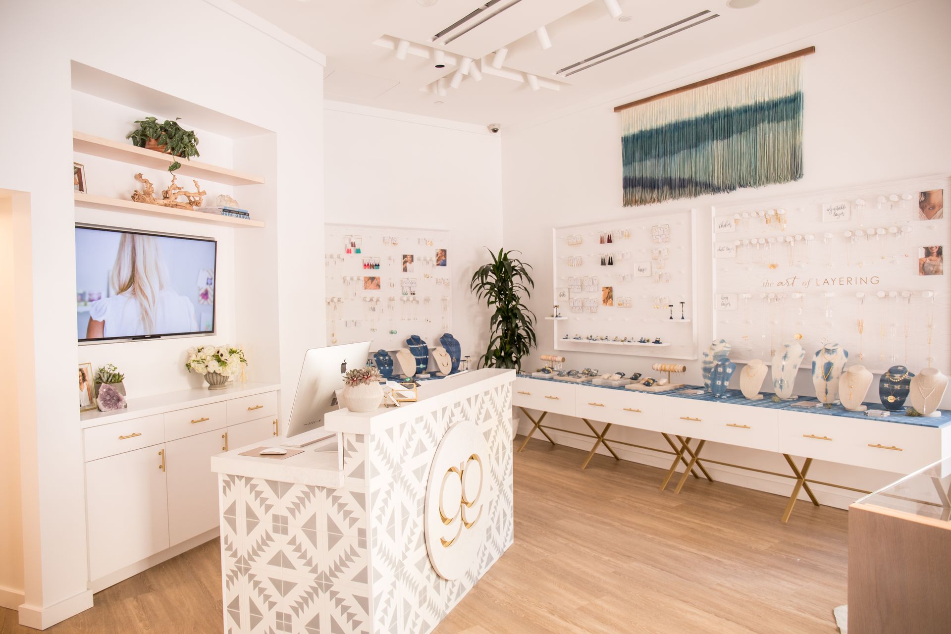 Bright white gallery with framed art, display shelves, and a central decorative table in a minimalist room