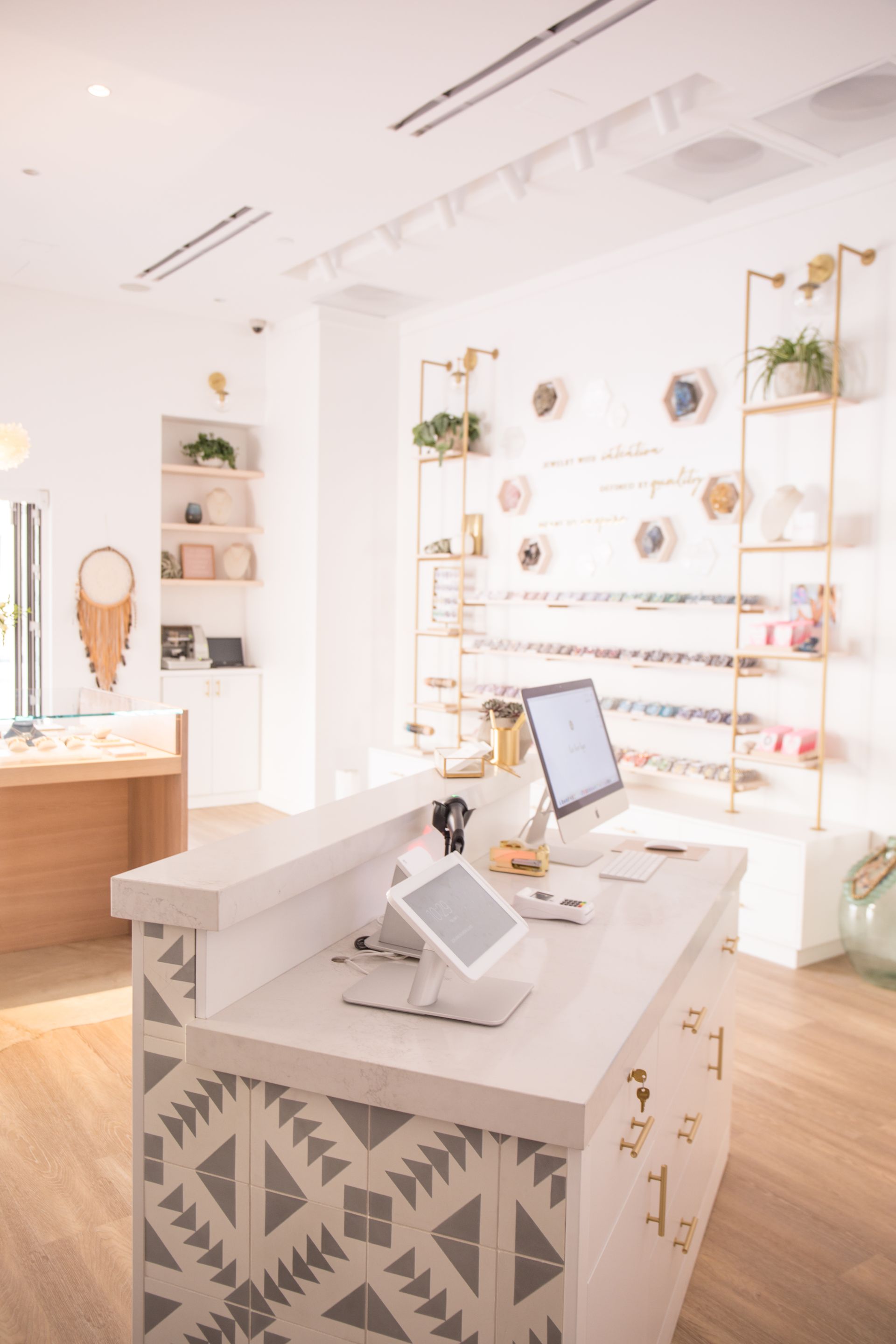 Bright boutique interior with white shelves, jewelry displays, and a decorated display counter