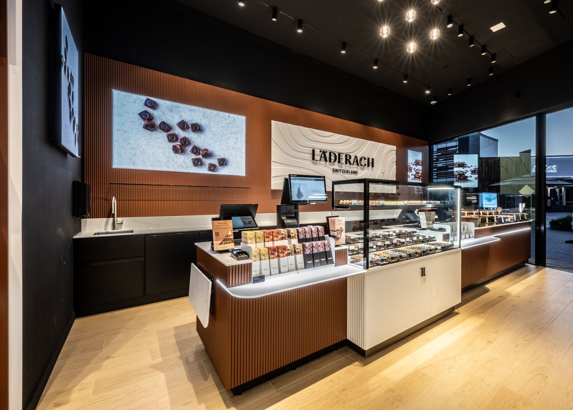 Modern bakery counter with display cases, wood accents, and pastries under warm spotlights
