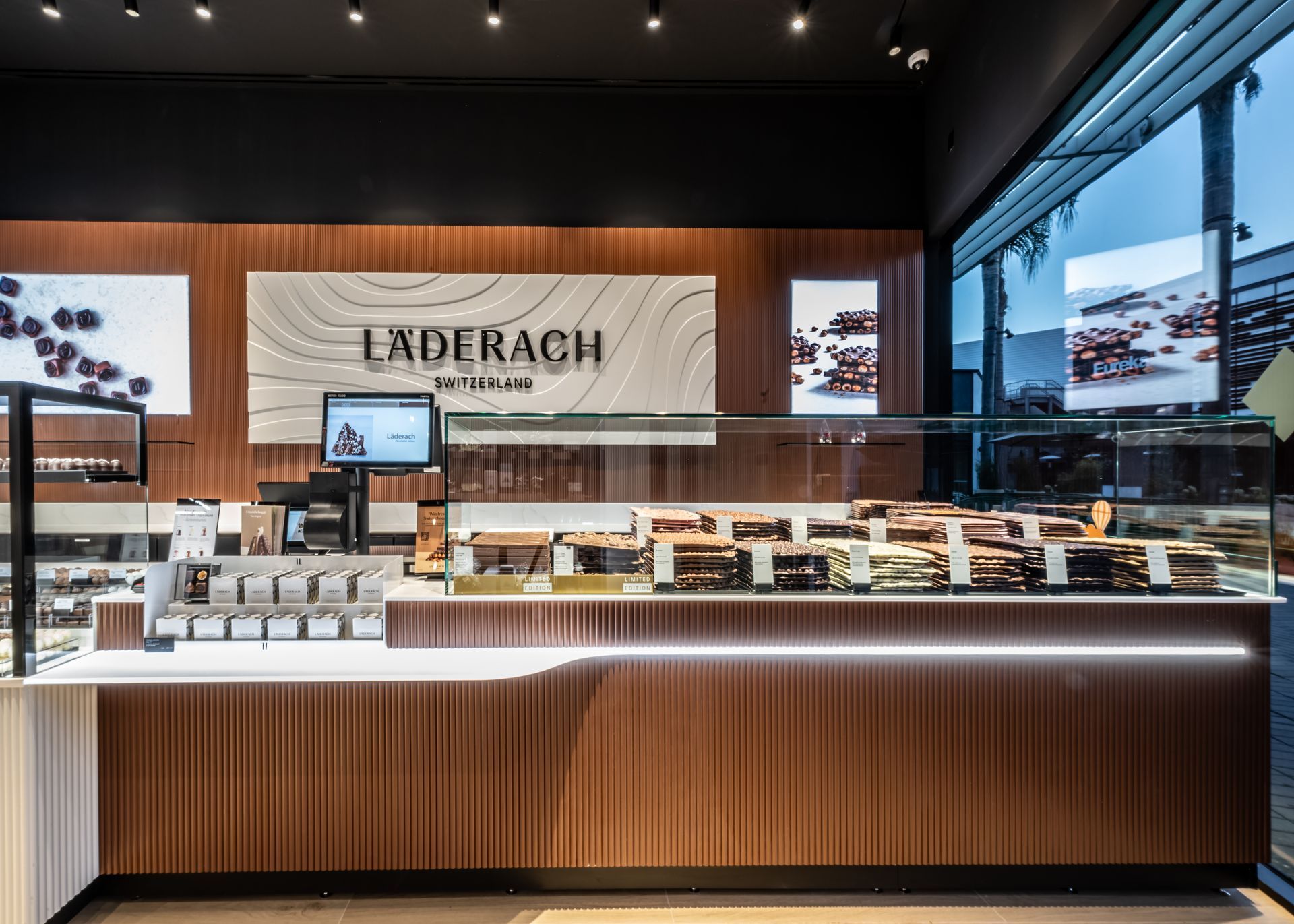 Laderach chocolate shop interior with wood counters, glass displays, and bright product shelves