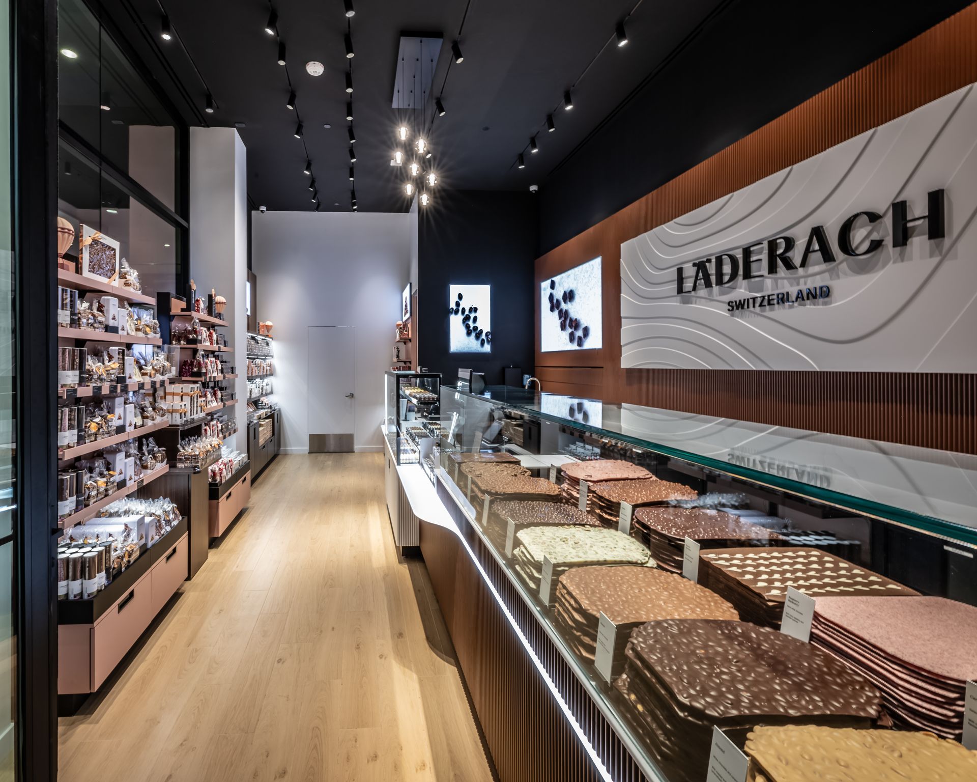 Luxury chocolate shop interior with display cases and Lindt branding on wood-paneled wall