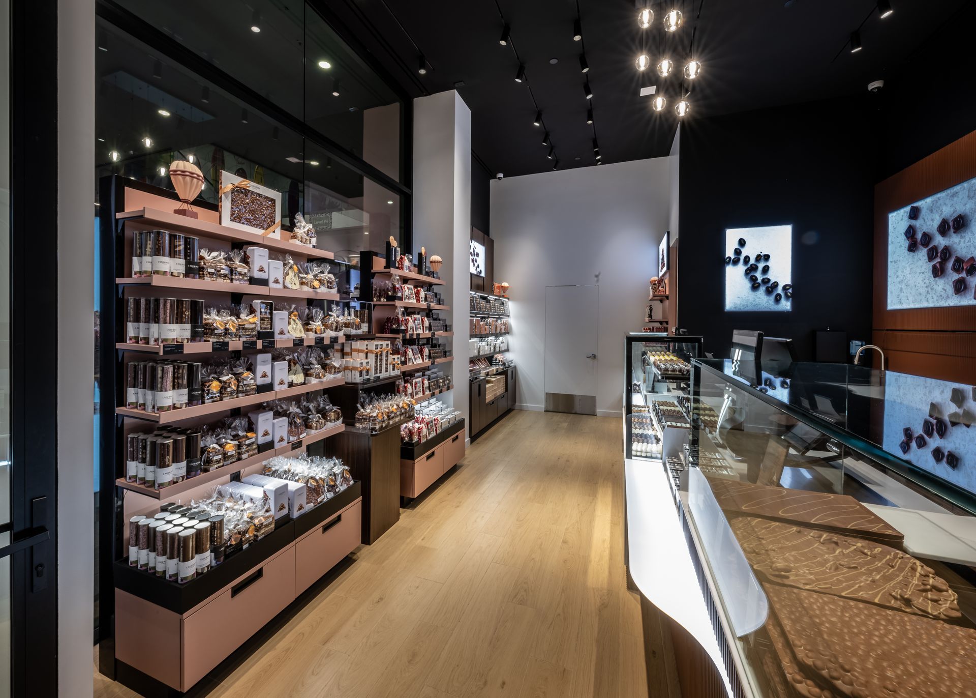 Bright modern cafe or shop interior with shelves of products and glass display counters under black ceiling lights