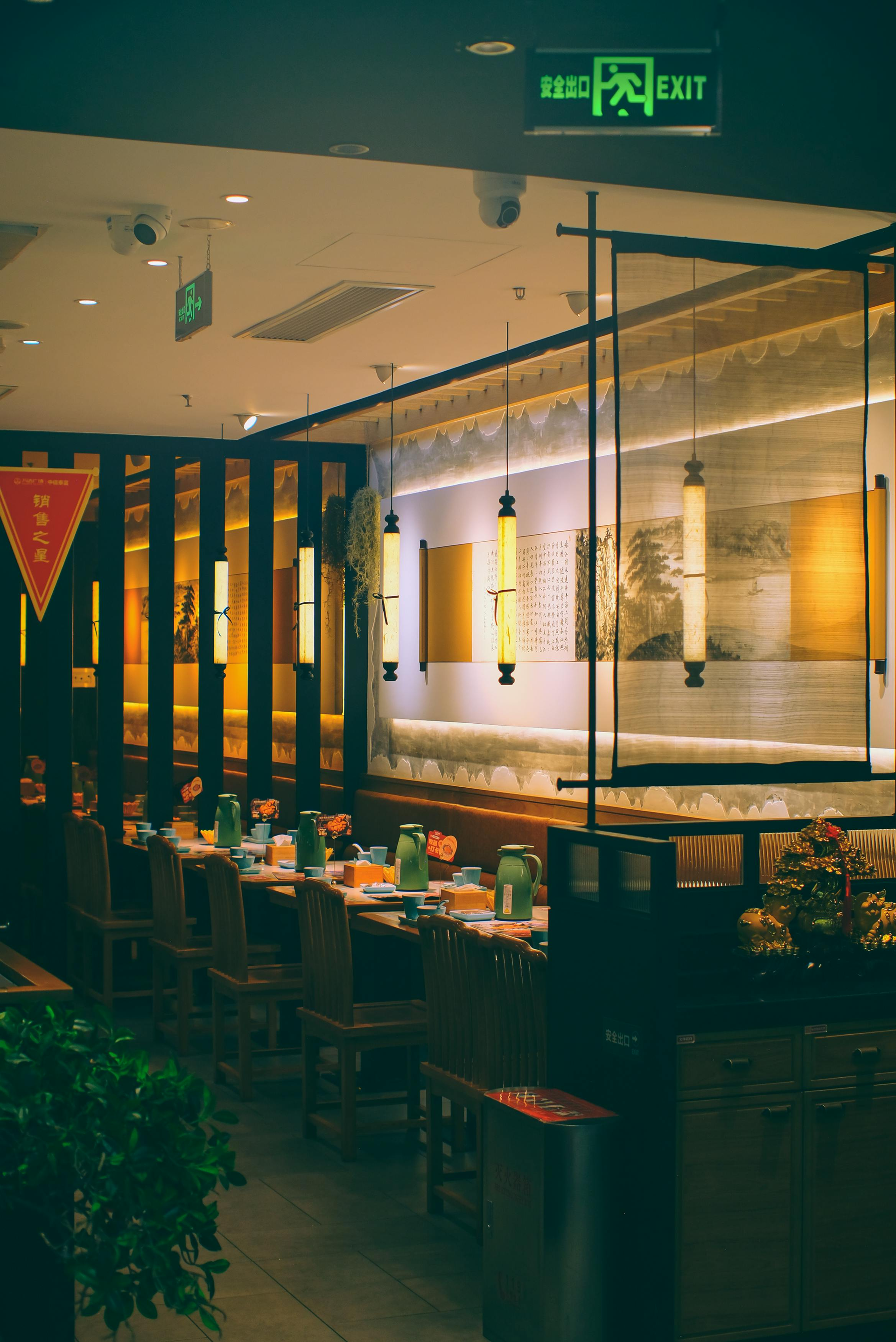 Empty modern restaurant interior with tables, warm lighting, and green signage above the entrance