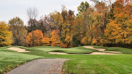 Golf course fairway with sand bunkers, green grass, and autumn trees in the background