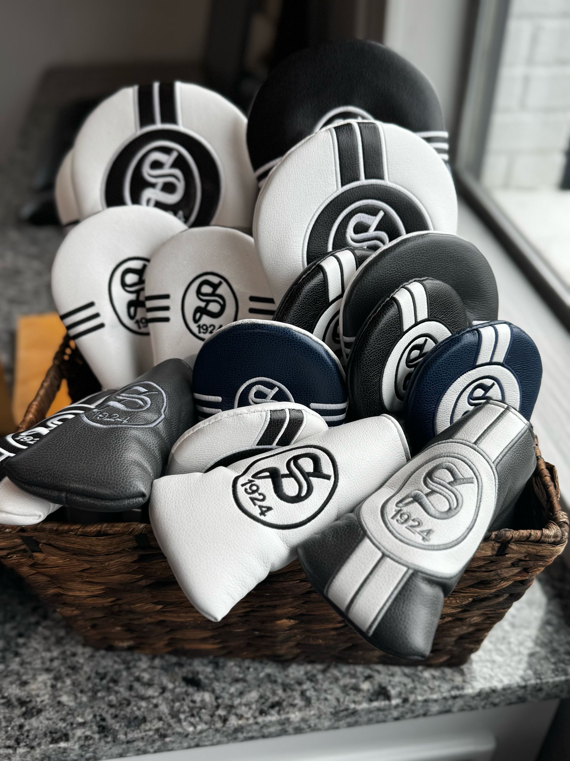 Assorted black, white, and gray golf club headcovers arranged on a countertop