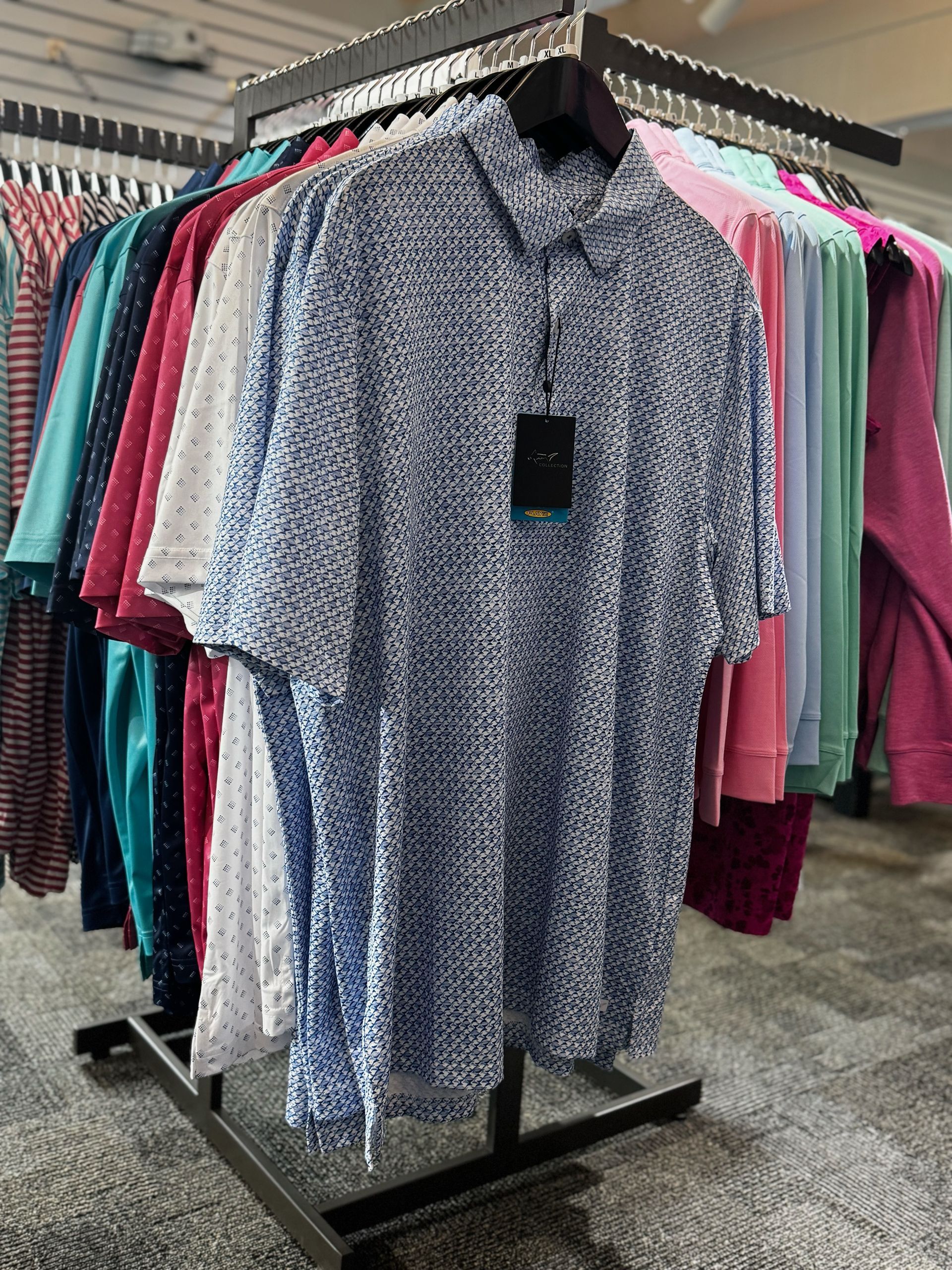 Blue floral short-sleeve shirt on a rack of colorful hanging clothes in a store