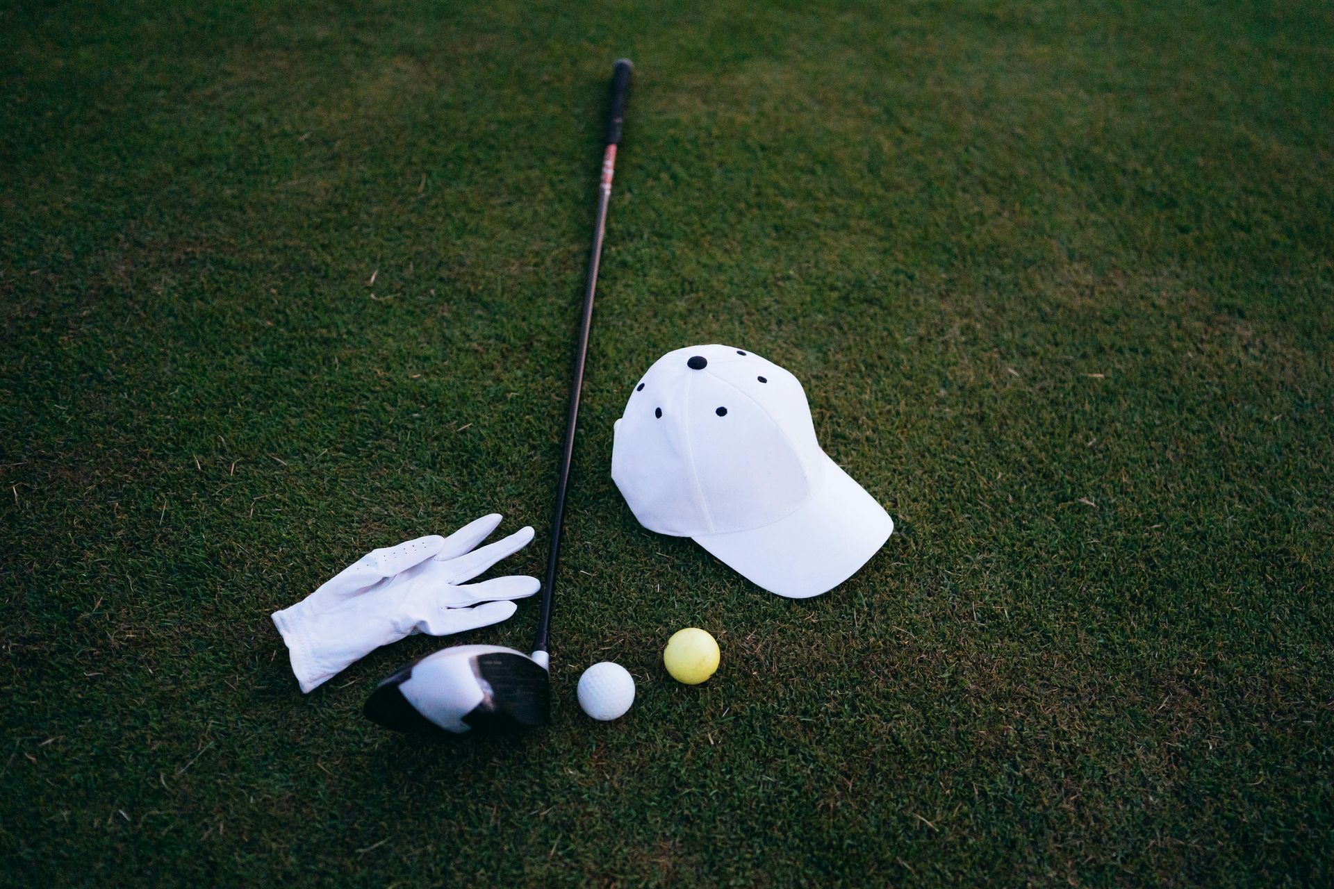 Three golf balls on tees in a grassy course with a blurred tree-lined background