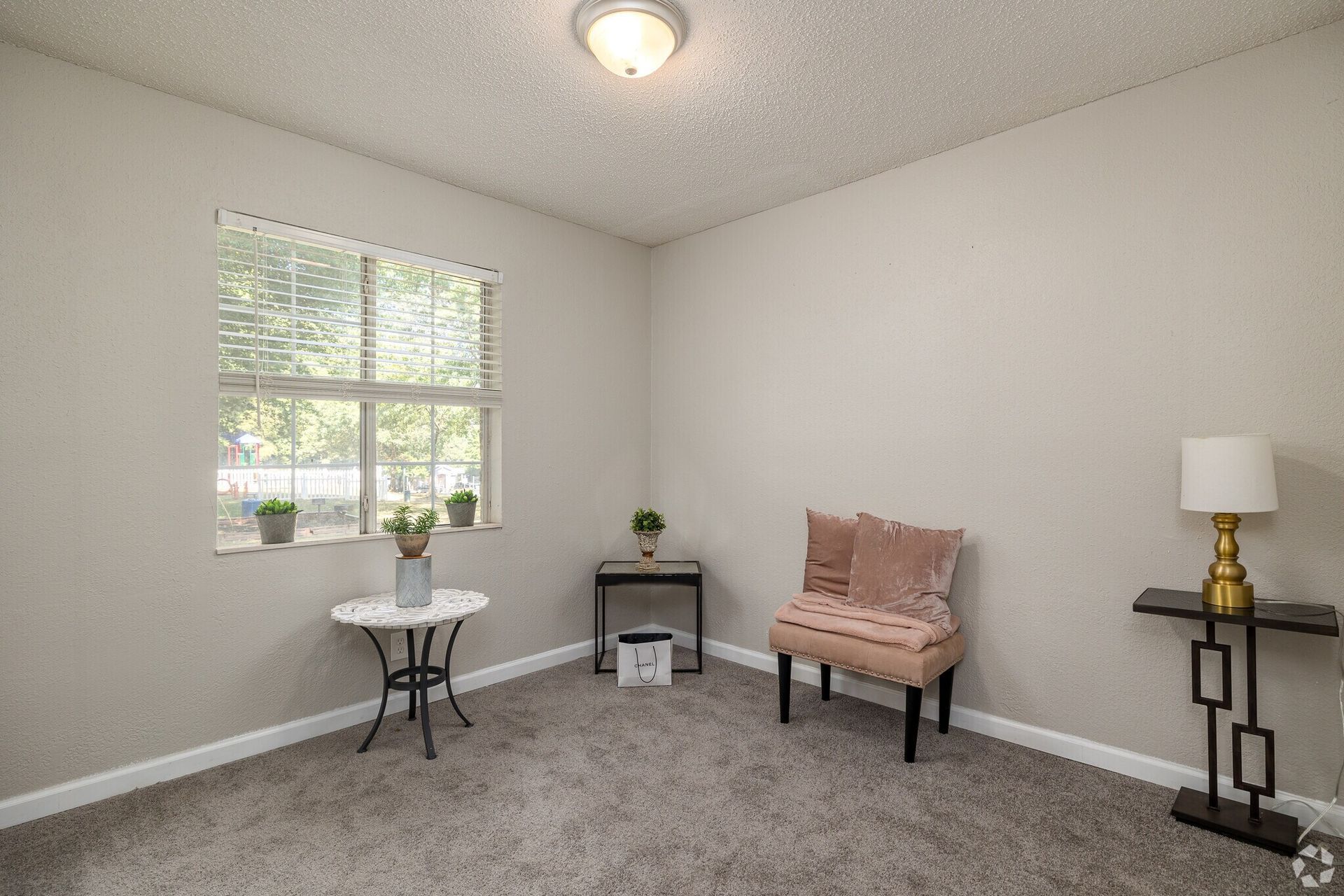 Photo of a room set up to function as a reading room, with a simple, plush chair and a couple of small side tables