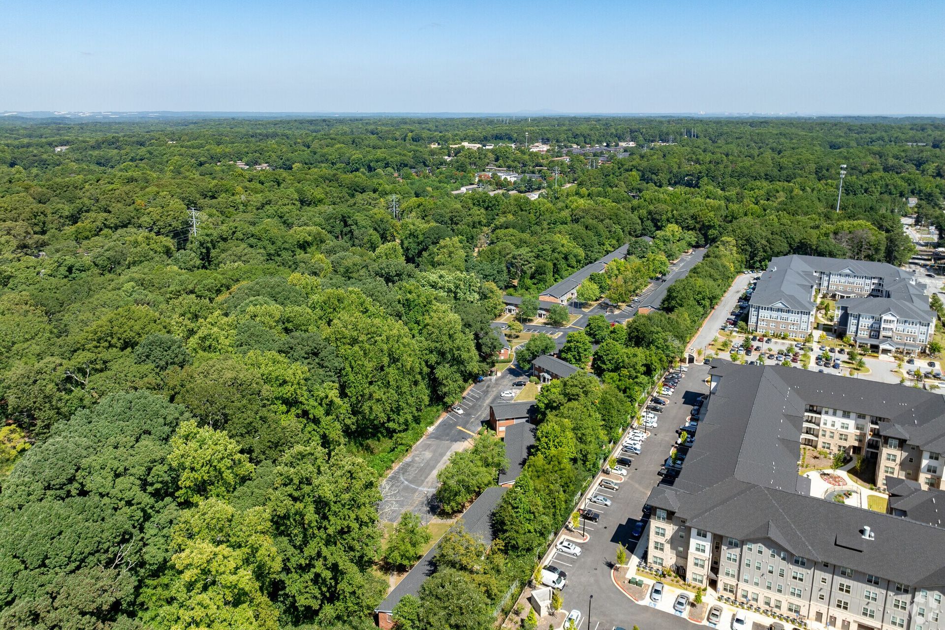 Photo of a neighborhood full of treese with two apartment buildings on the right side of the photo