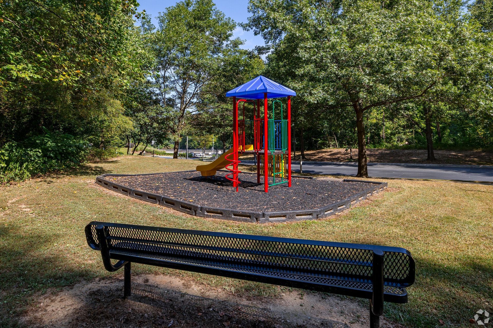 Photo of a small playground area, with a nearby bench