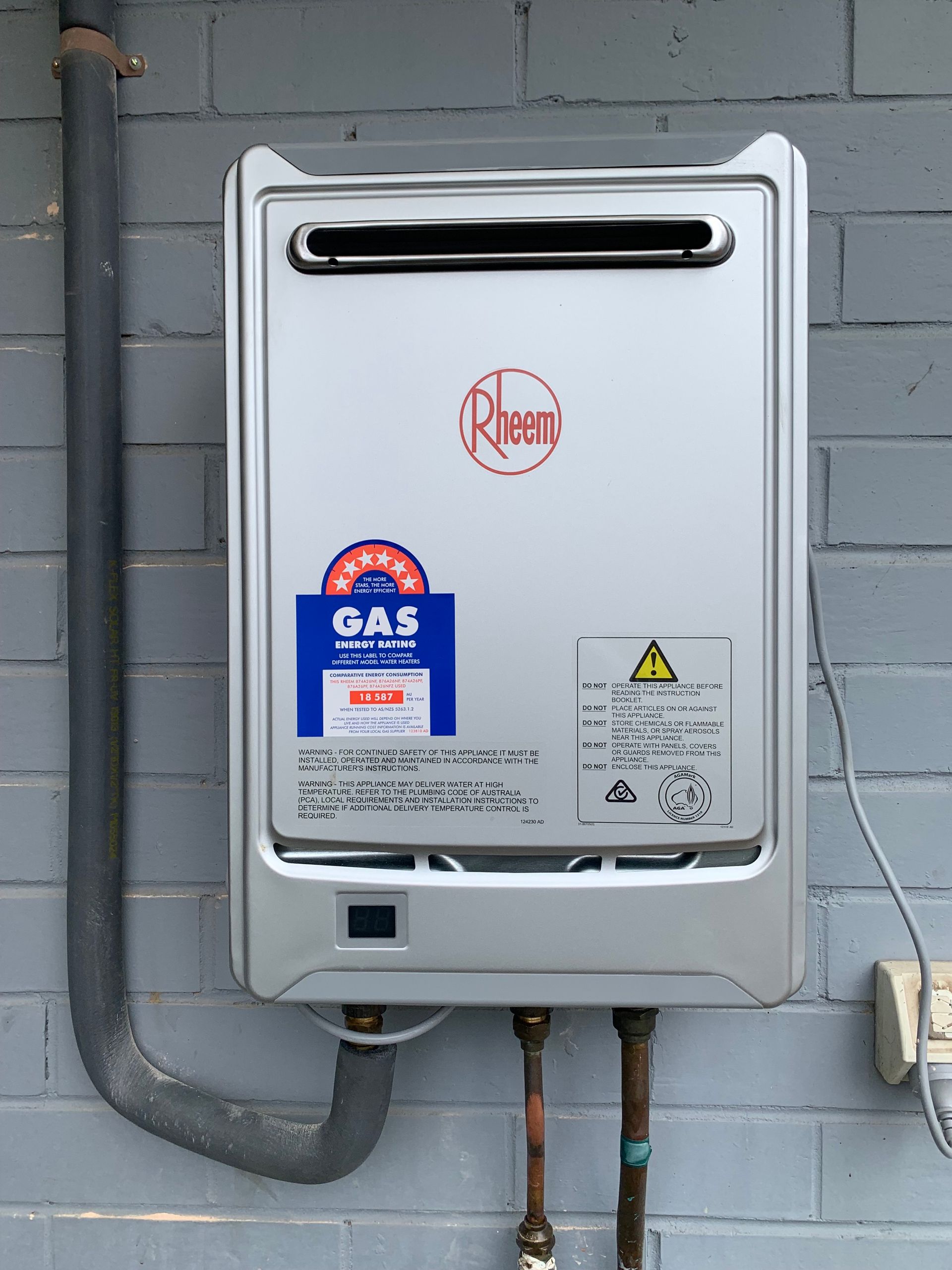 A White Water Heater is Attached to a Brick Wall — Corbett Plumbing in Ballarat, VIC