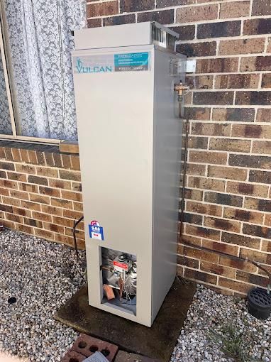 A Large White Water Heater is Sitting in a Room Next to a Window — Corbett Plumbing in Ballarat, VIC