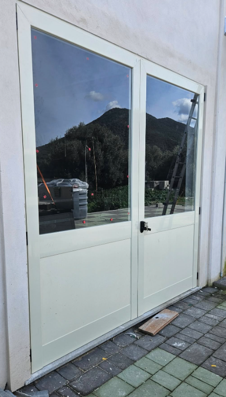 Porte a doppi vetri, telaio bianco, che riflettono un paesaggio montano.