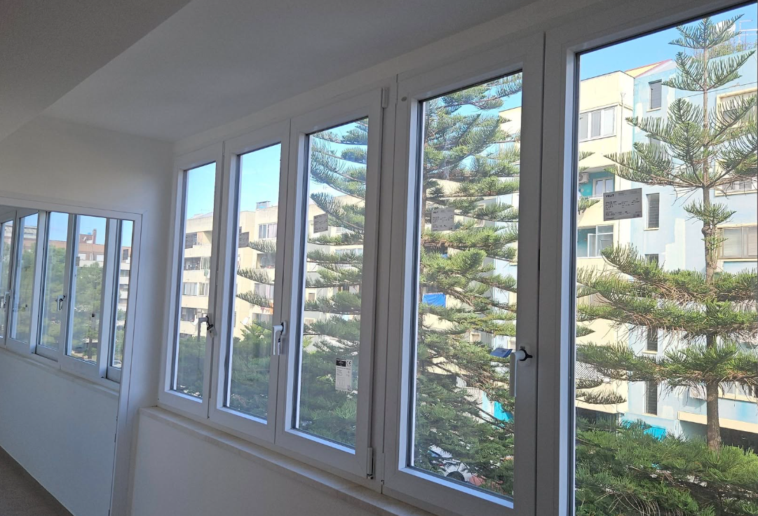 Finestre con cornice bianca che si affacciano sulla città e sugli alberi.