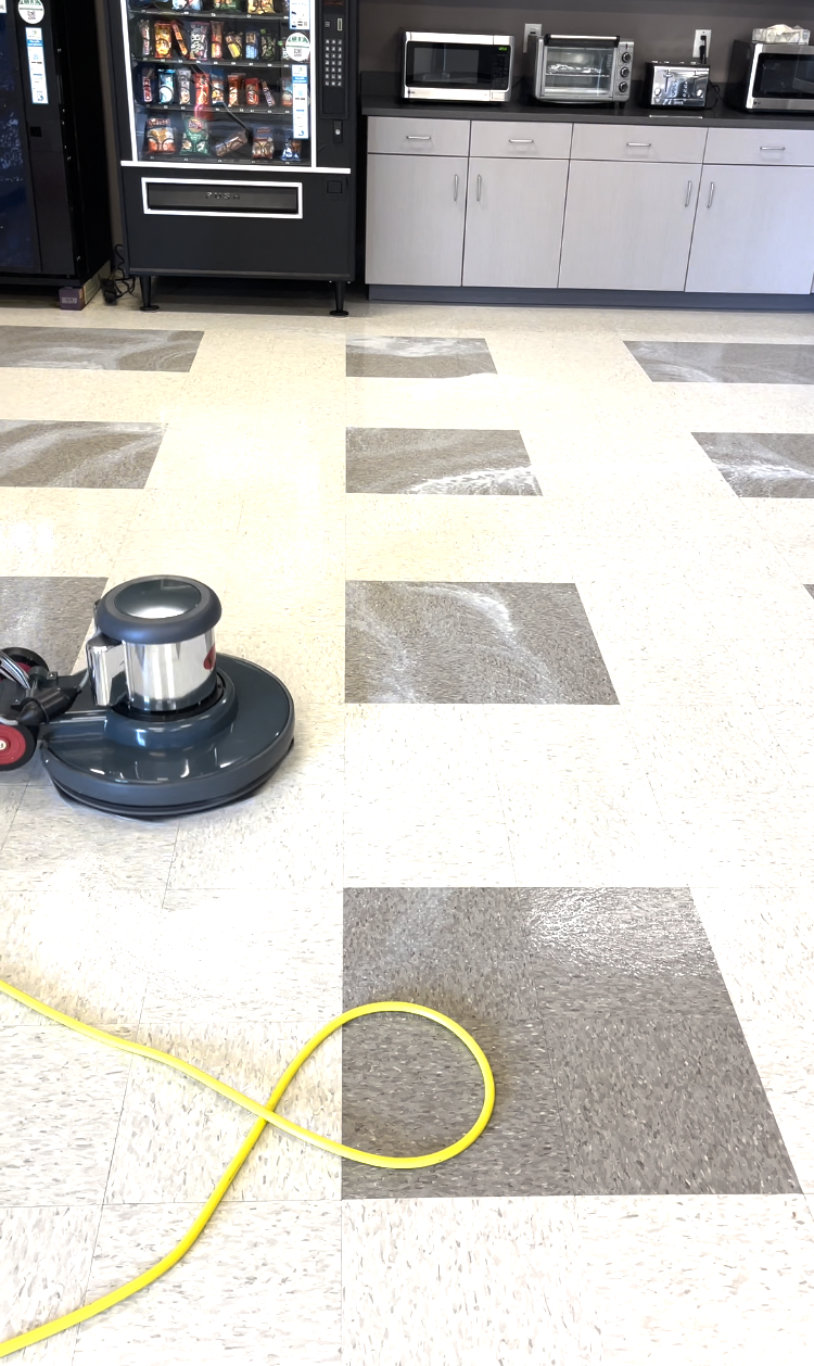 A machine is being used to clean a tiled floor in a kitchen.