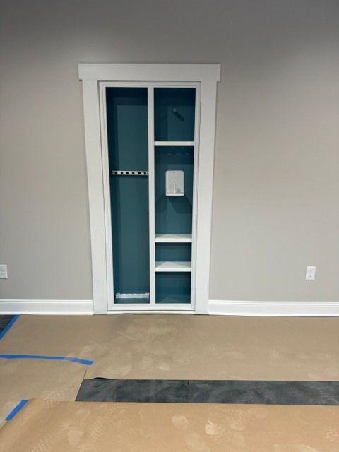 Empty room with a white-trimmed closet door on a gray wall and unfinished flooring.