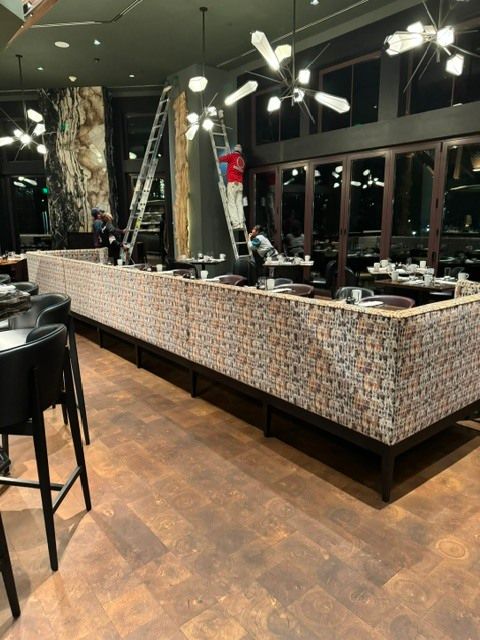 Empty modern restaurant interior with tiled bar seating, dark floors, and hanging lights