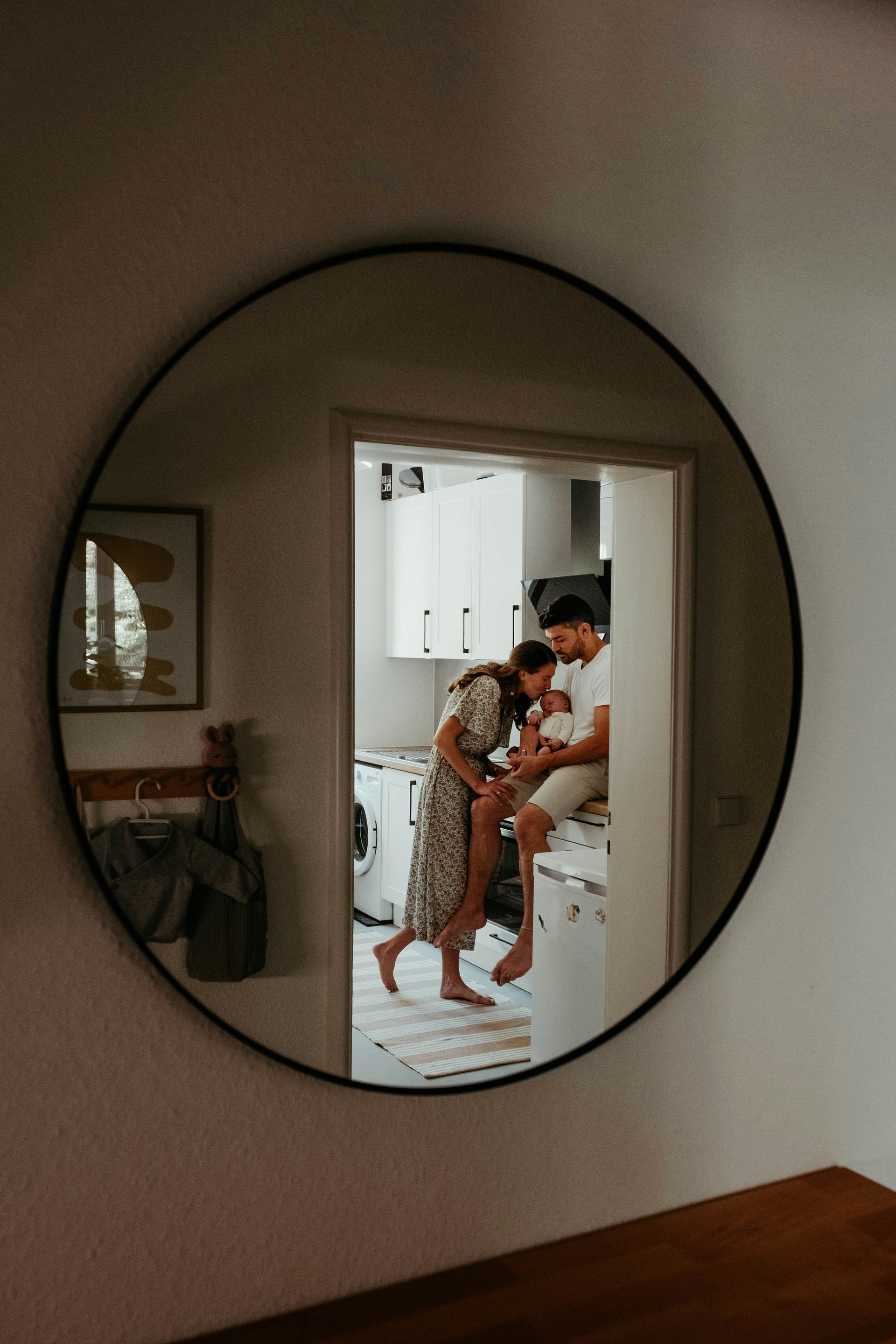 A man and a woman are standing in front of a round mirror.
