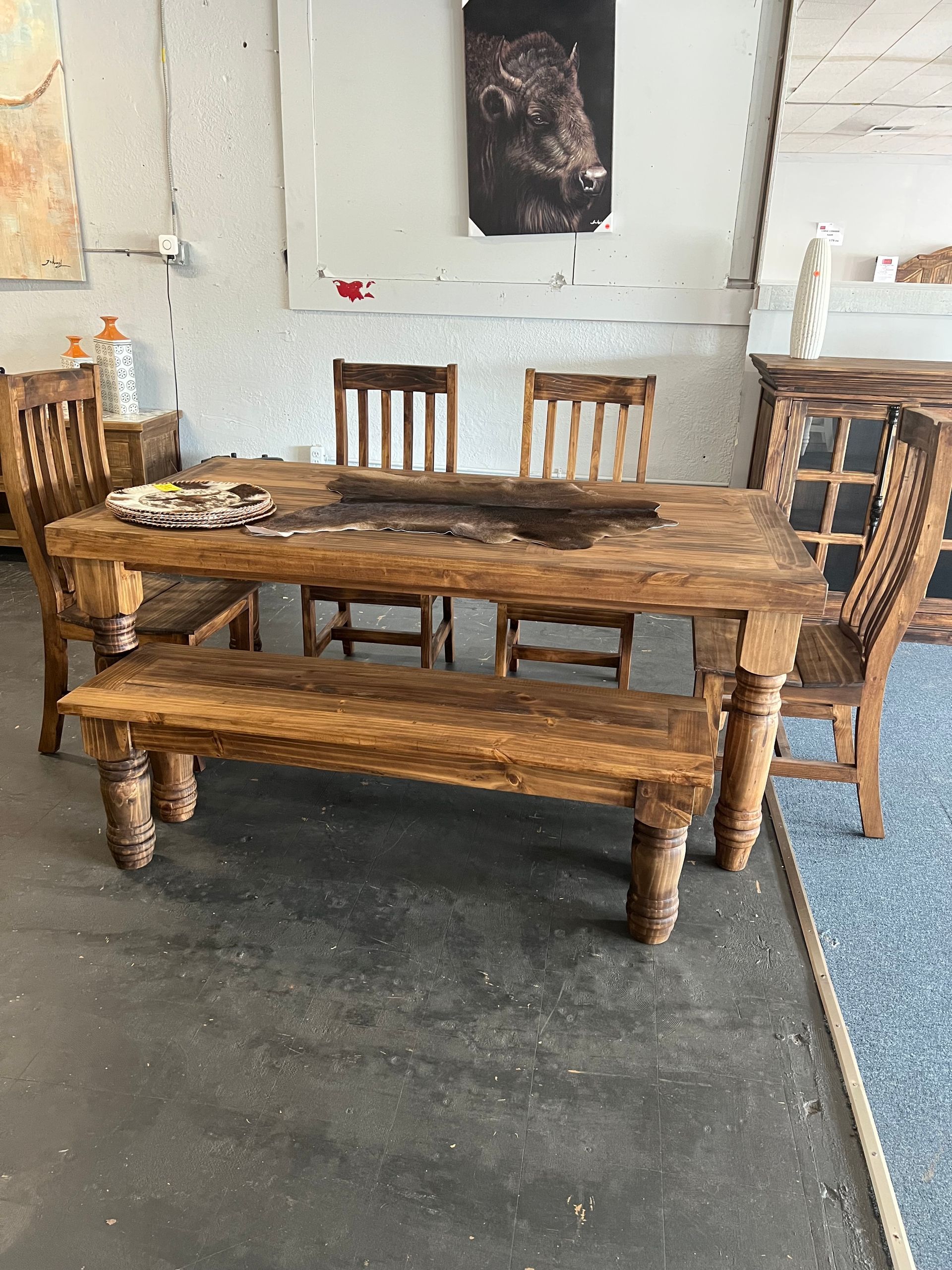 Wooden dining table set with bench and chairs on carpet.
