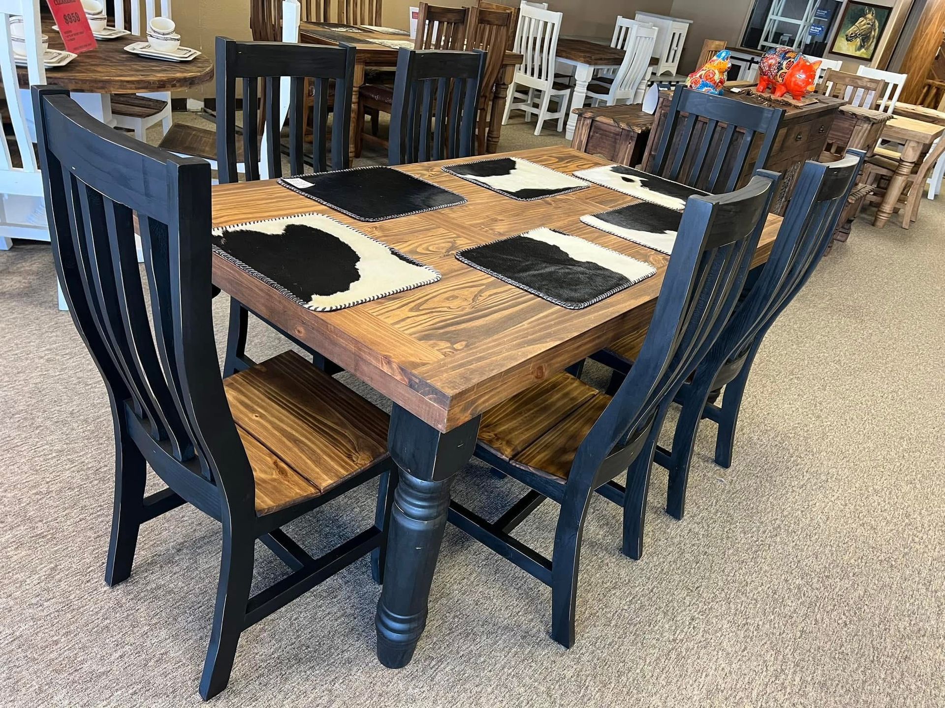 Dining room with wooden table and six black chairs, under a chandelier.