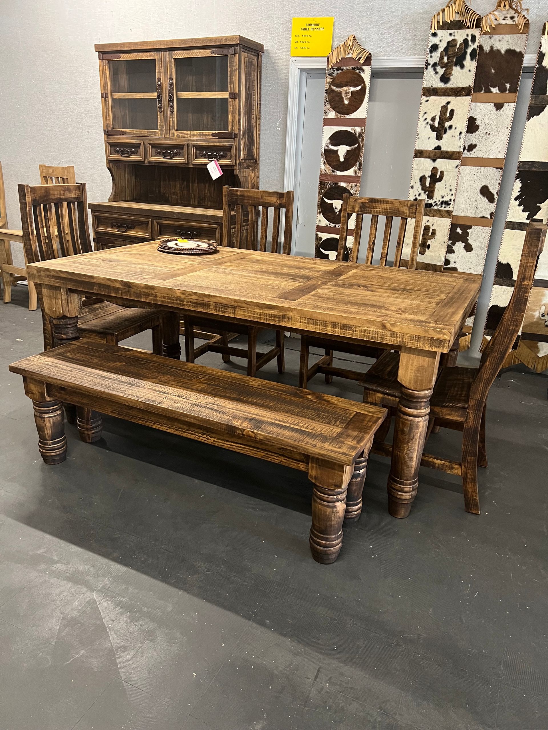 Rustic dining room with wooden table, chairs, bench, and decorative wall panels.