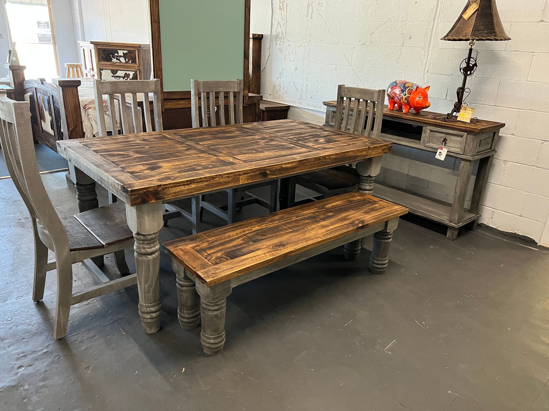 Rustic dining table set with chairs and bench in a showroom.