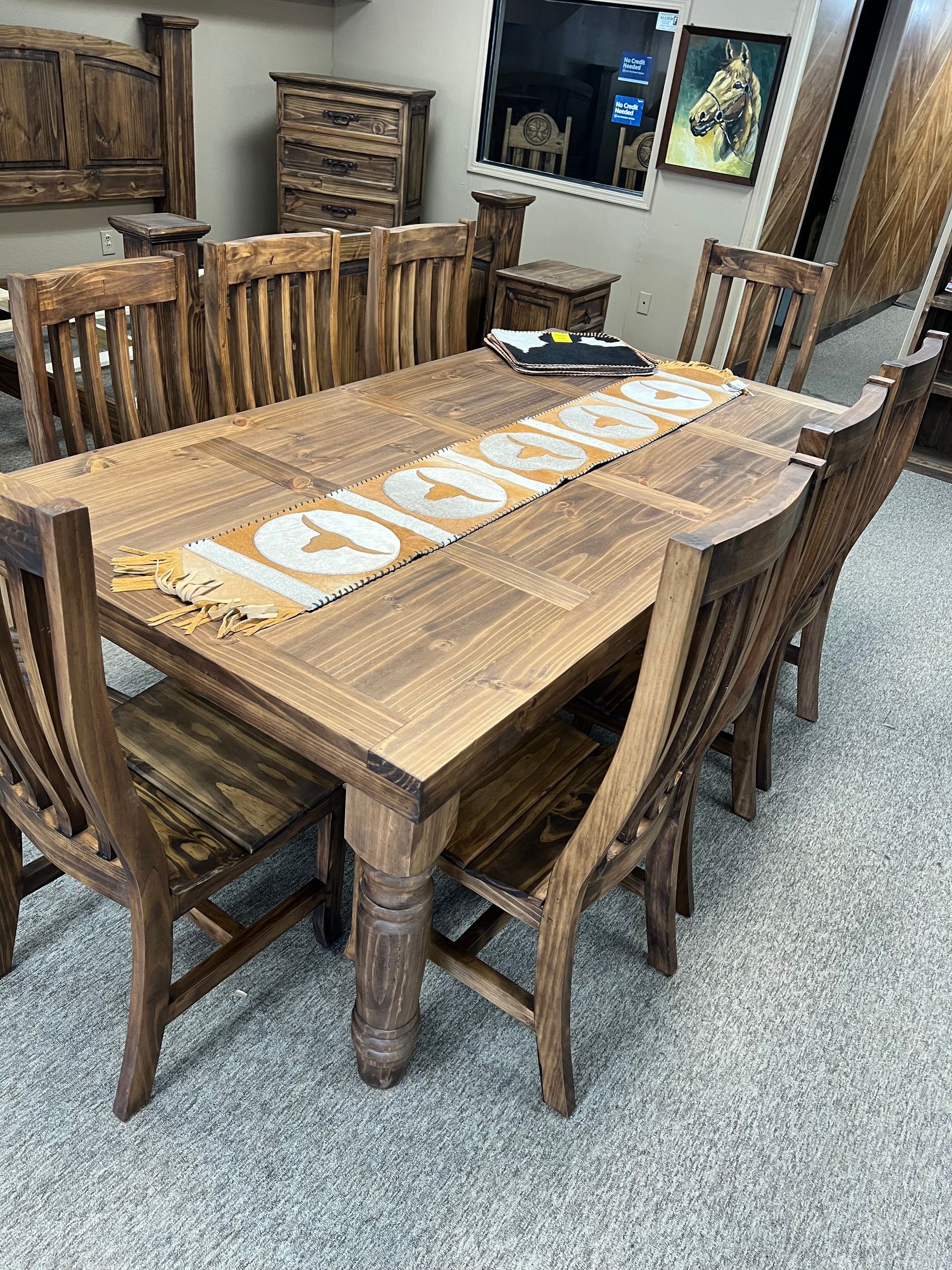 Wooden dining table with eight matching chairs in a store setting.