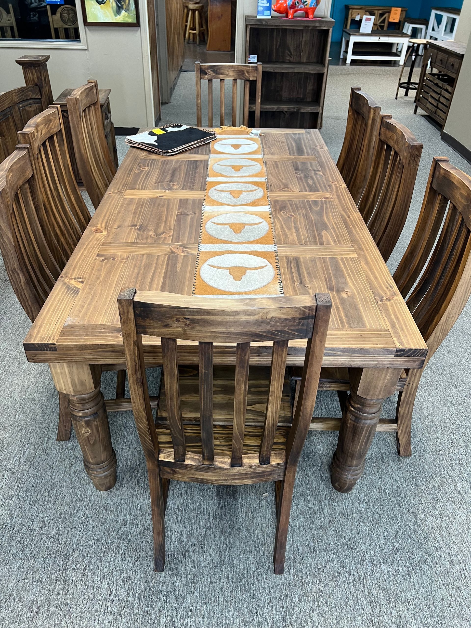 Wooden dining table with eight matching chairs in a store setting.