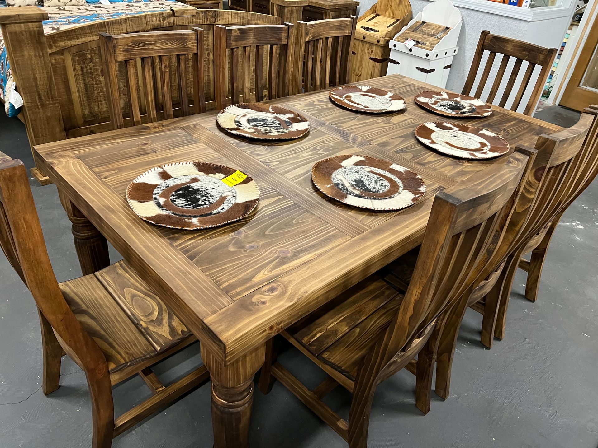 A wooden dining table set with six chairs and decorative plates.