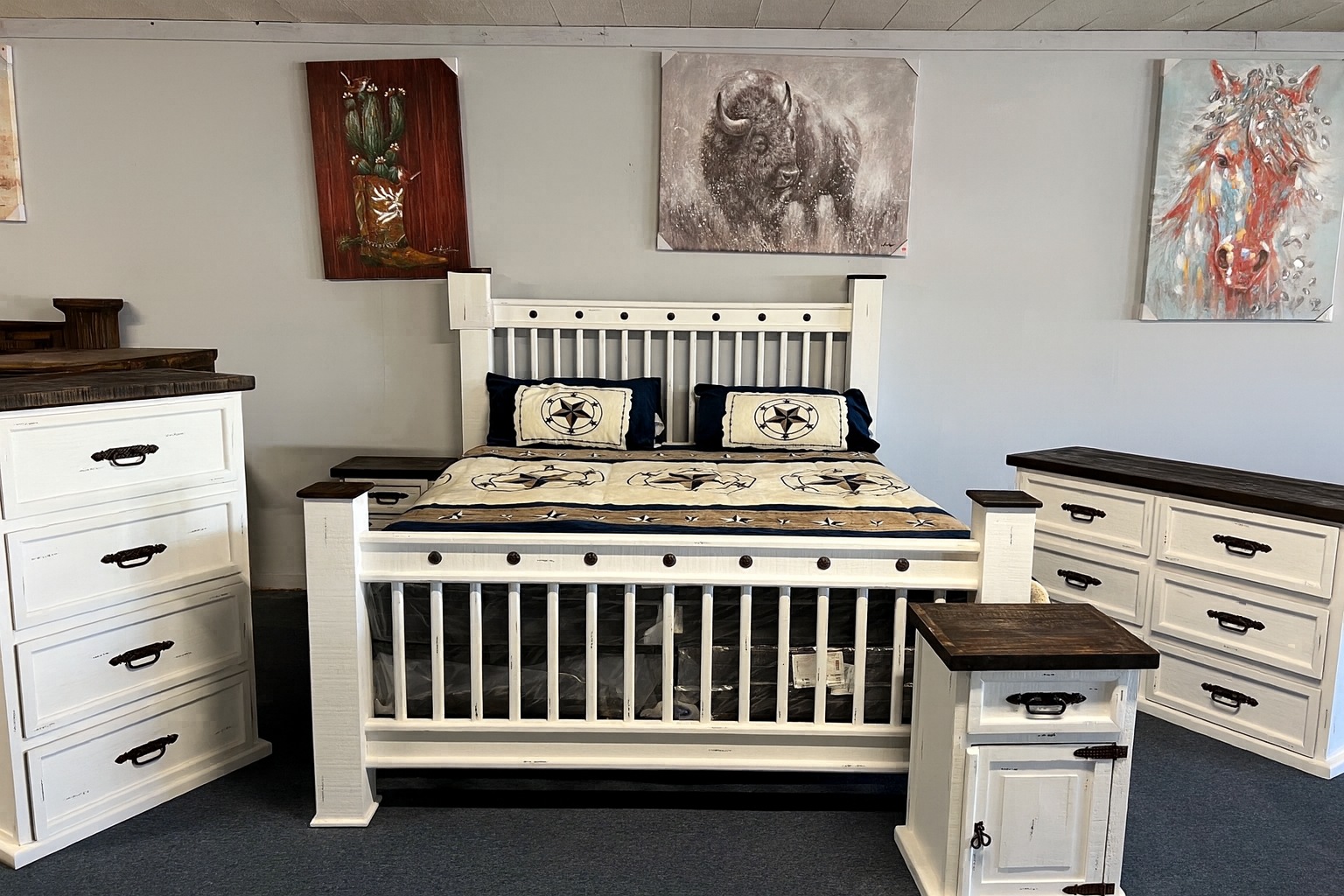 Farmhouse bedroom set: white bed frame, dresser, and chest with a cow painting and round mirror.