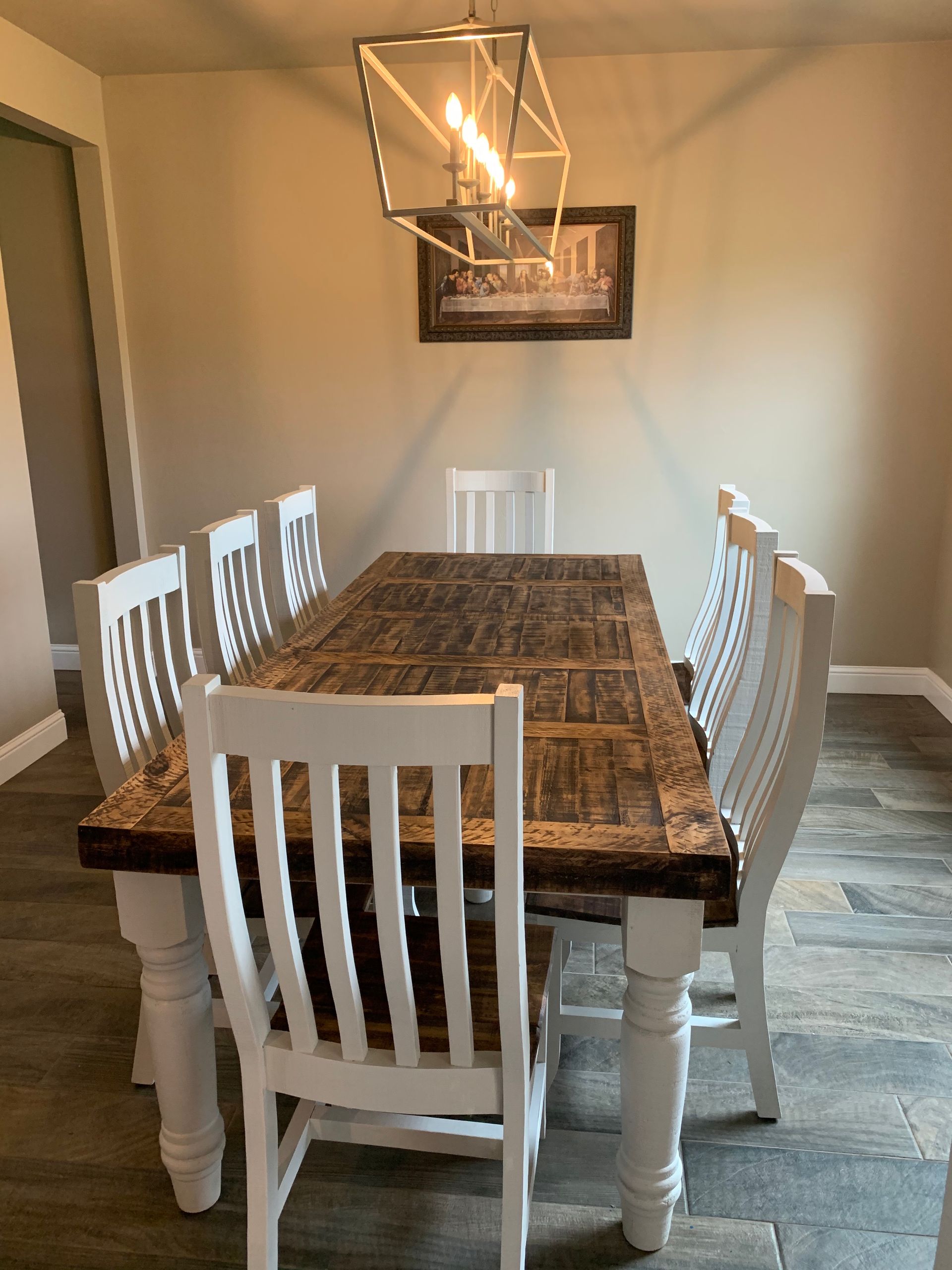 Dining room with a long, wood table, white chairs.
