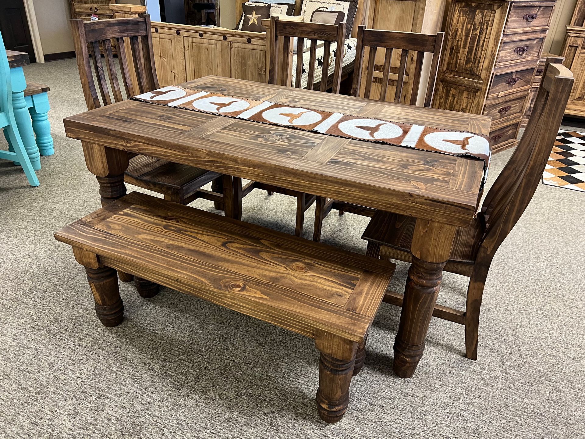Wooden dining table set with bench and chairs on carpet.
