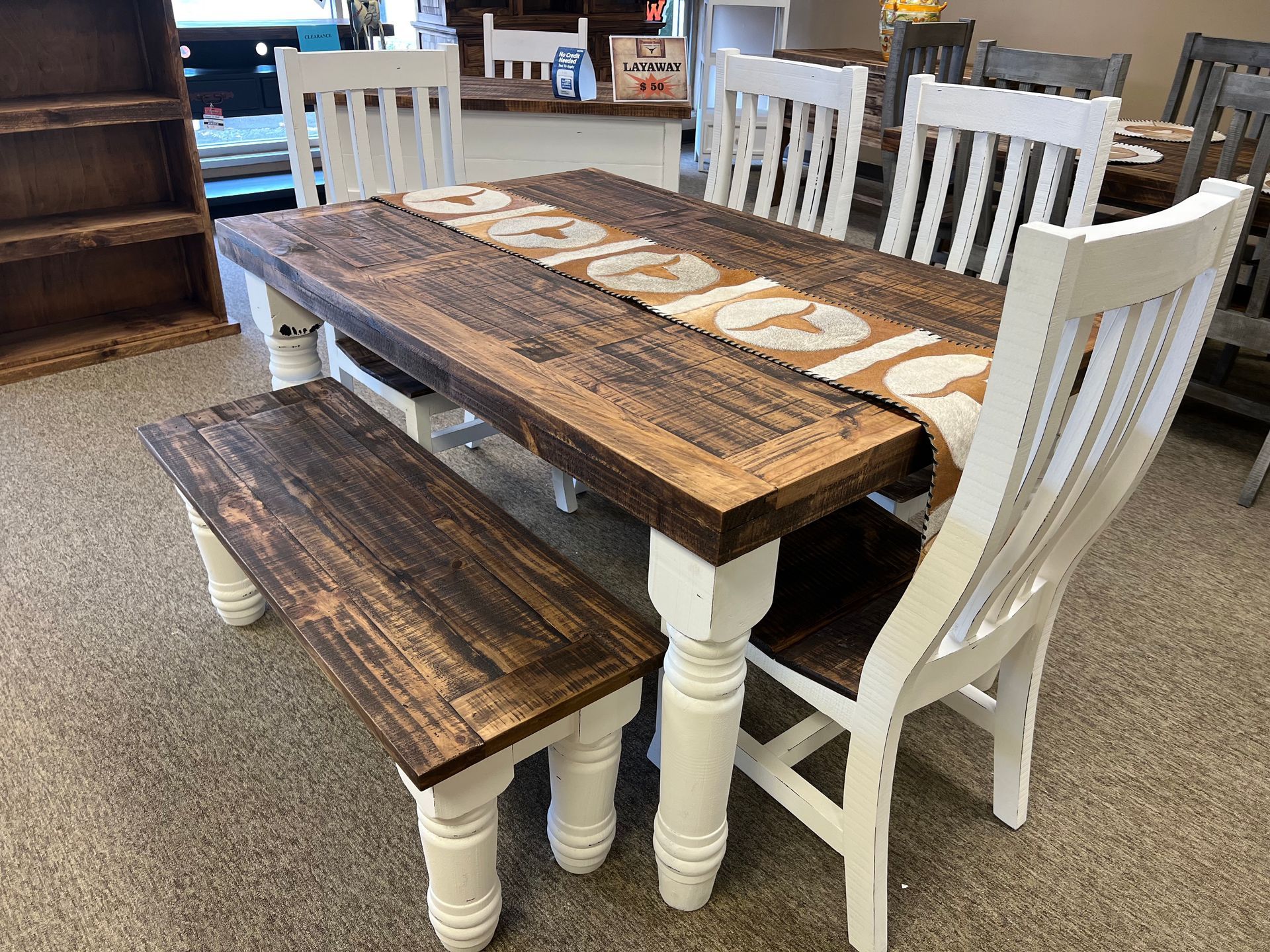 Wooden dining set: brown tabletop, white legs/chairs, bench. Beige runner, light-colored flooring, indoor setting.