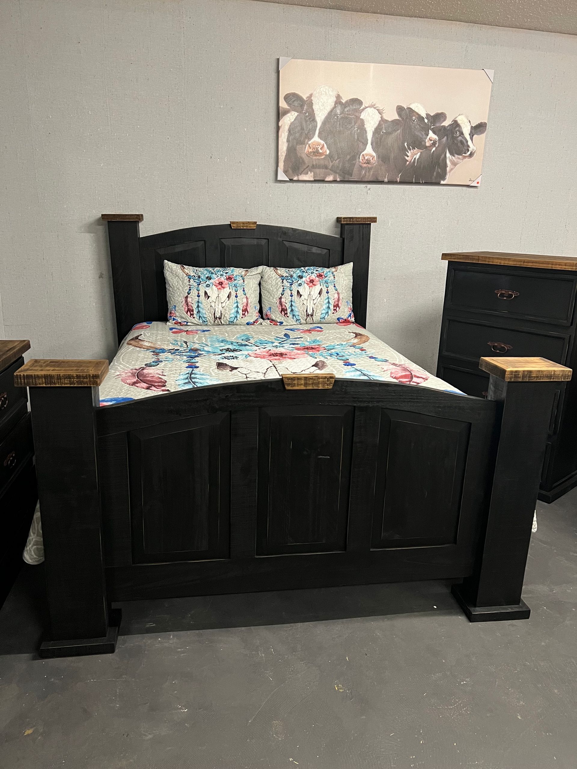 Bedroom with black wooden furniture and cow artwork.