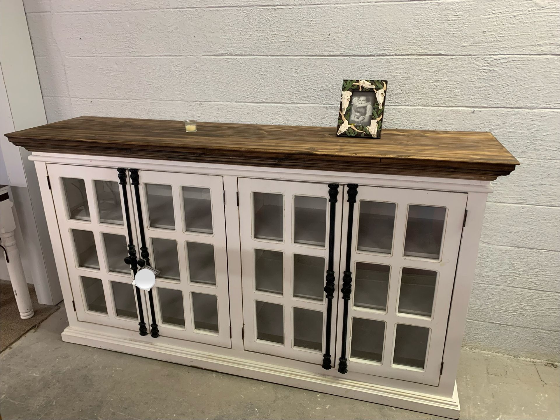 Wooden cabinet with glass doors, dark brown finish, sitting on blue carpet, items on top.