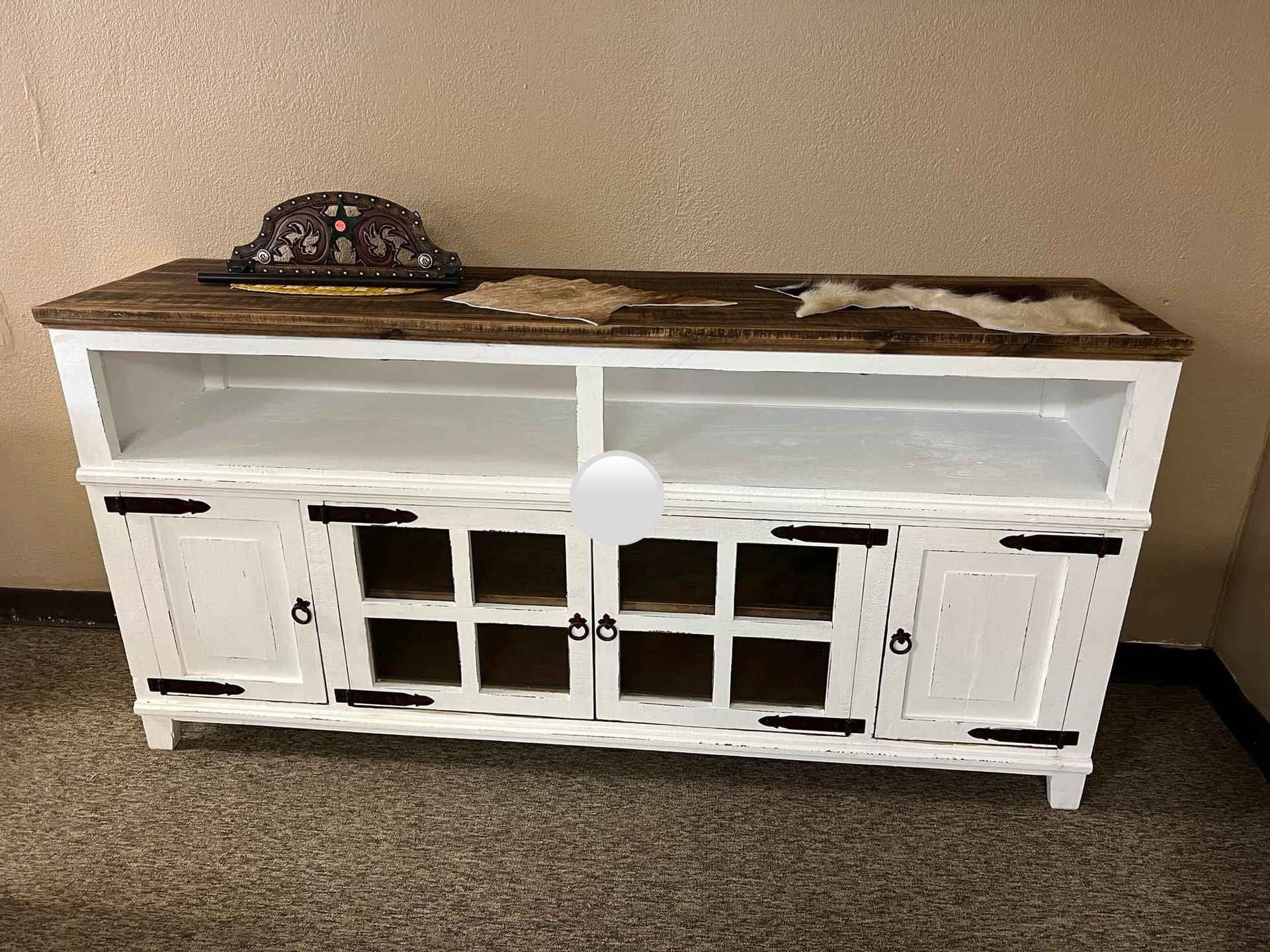 Wooden TV stand with cabinets, shelves, and decorative items in a store.