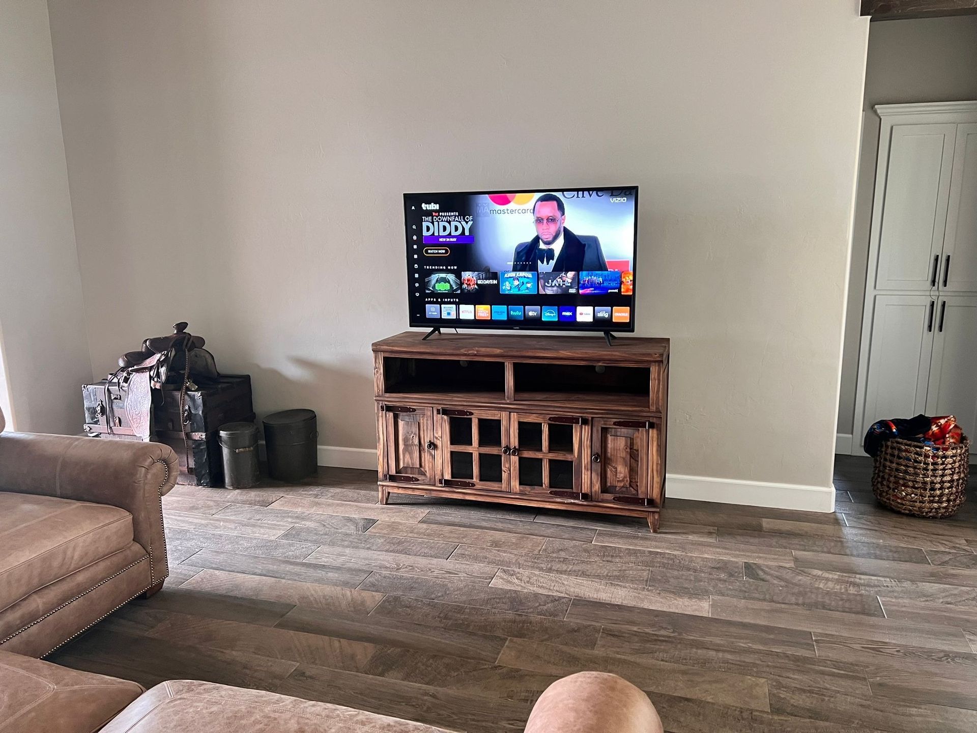 A TV on a rustic wooden stand displays a show. A couch and a cabinet are nearby.