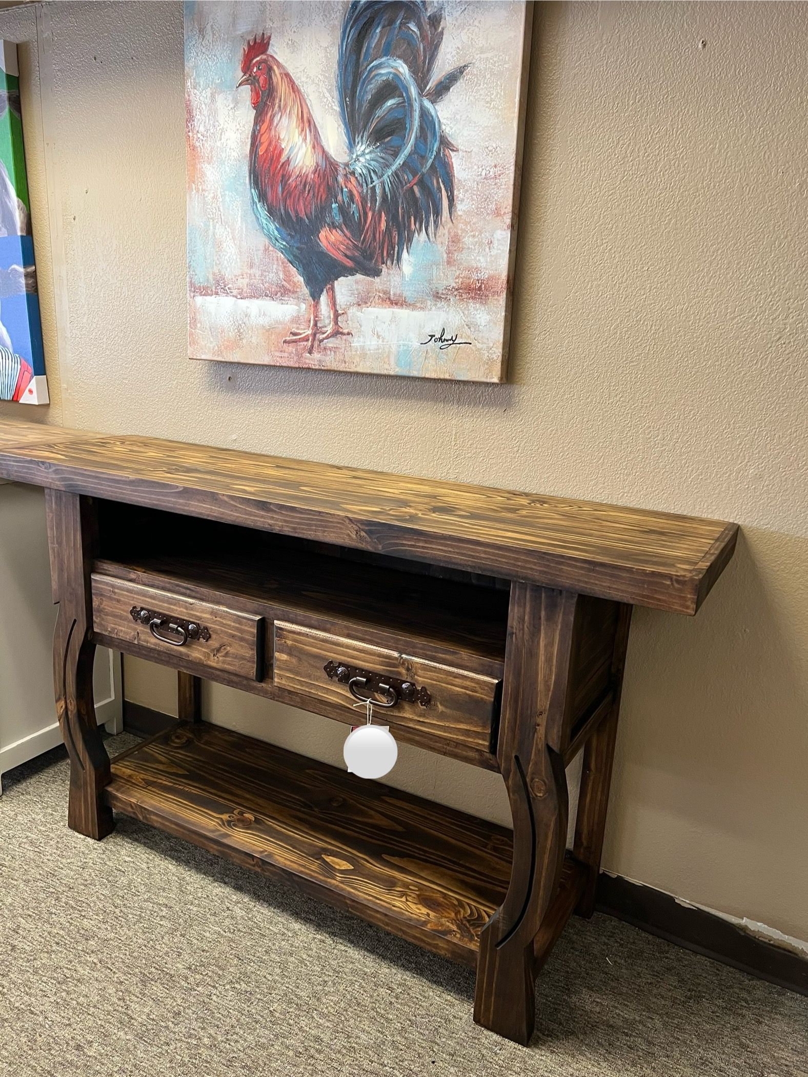 Rustic wooden console table with two drawers, rooster painting above.