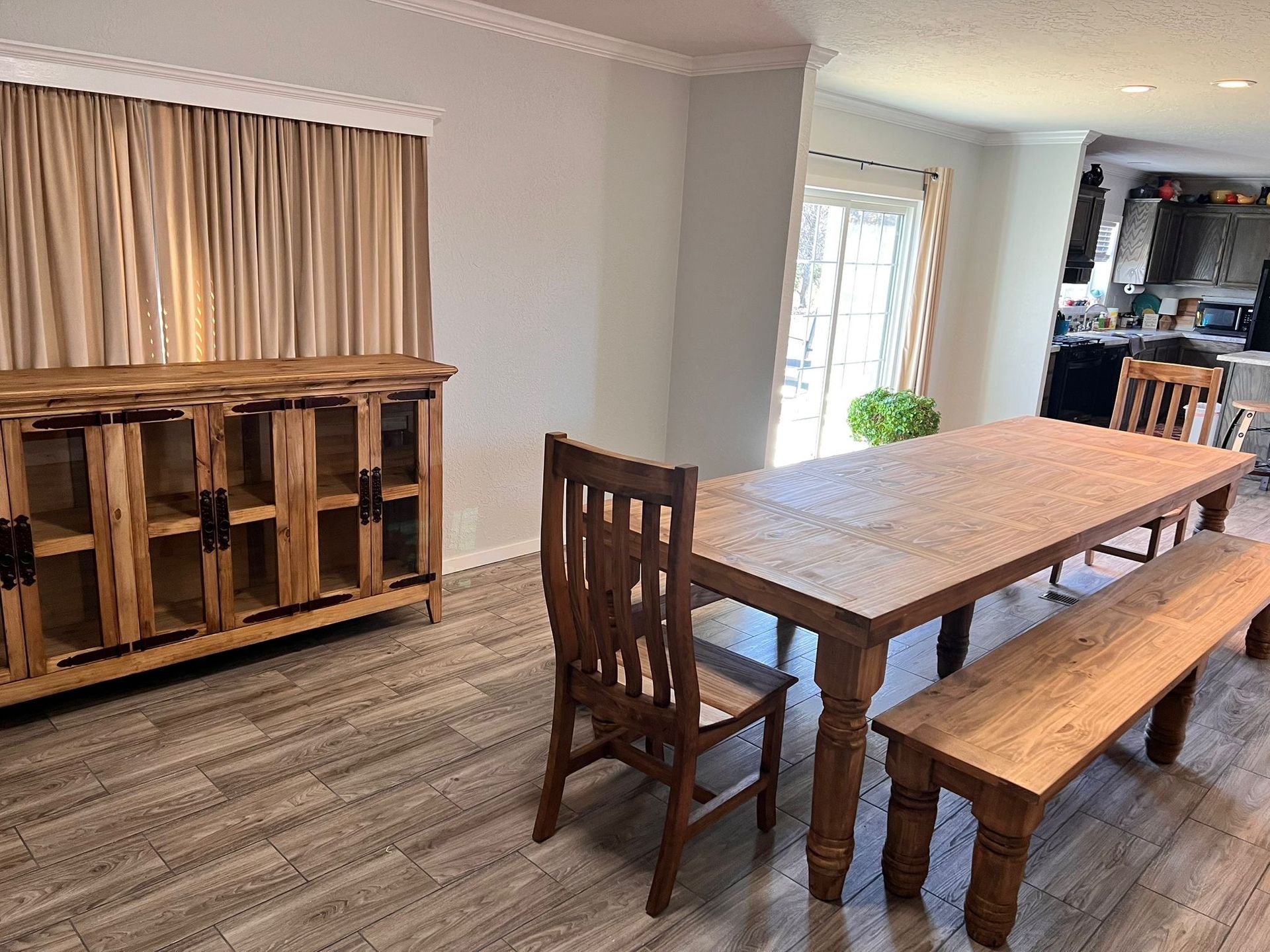 Dining room with wood table, bench, chairs, and buffet. Neutral colors.