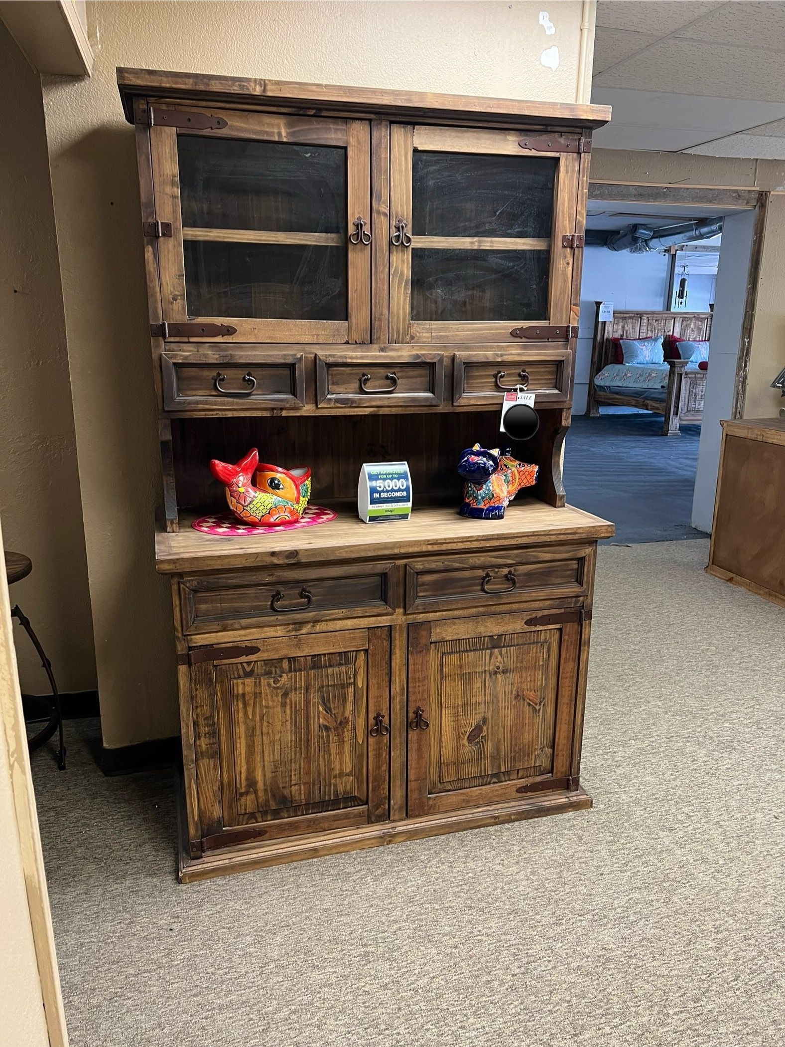 Wooden hutch with glass-door upper section, drawers, and cabinet doors; stained dark brown.