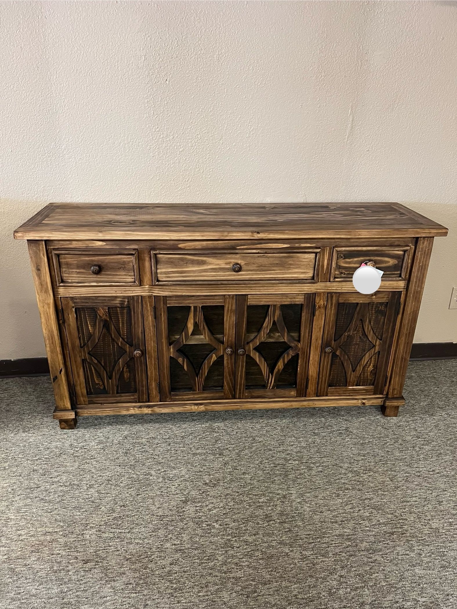 Wooden rustic buffet with drawers and carved doors.