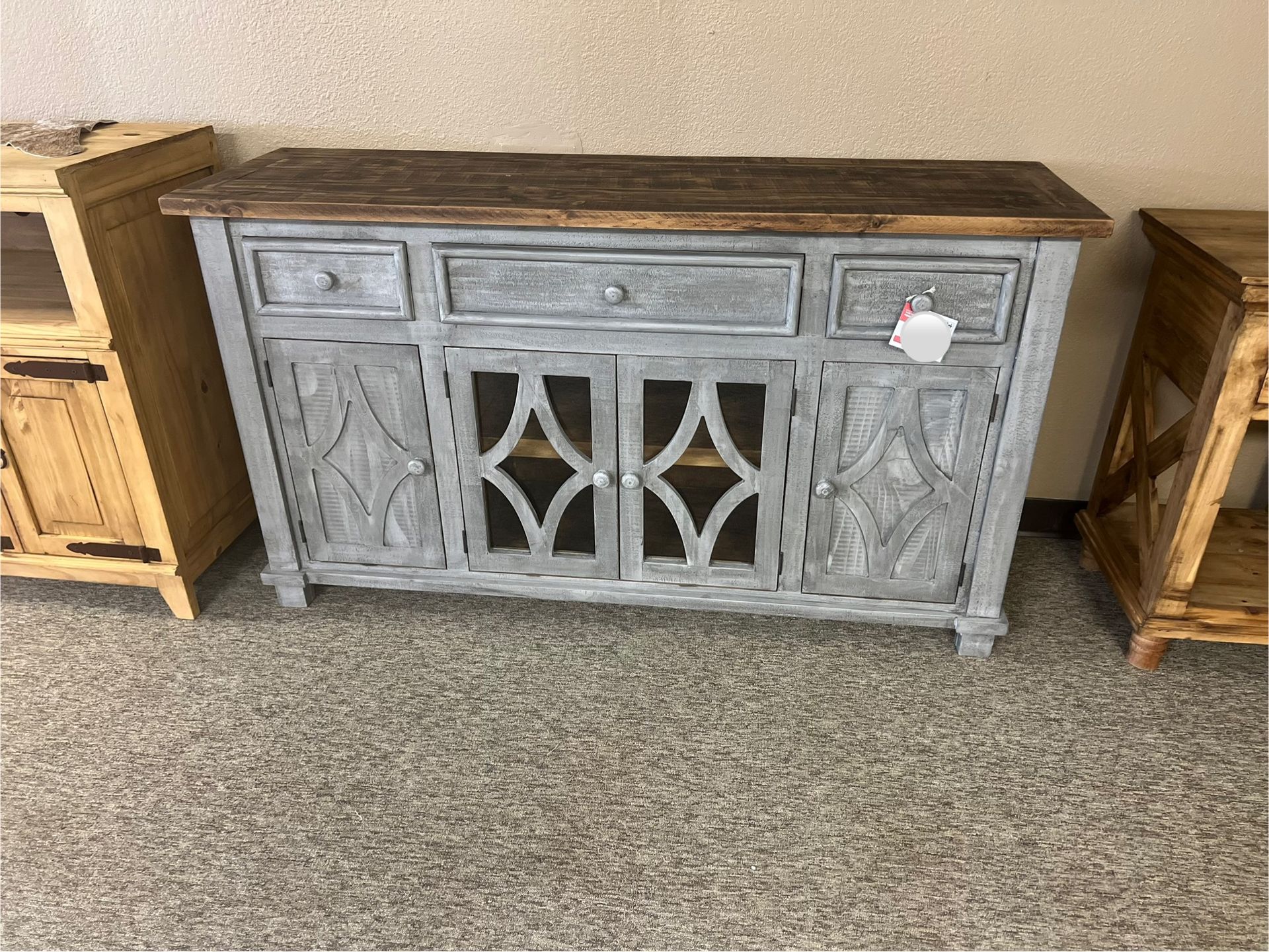 Wooden rustic buffet with drawers and carved doors.