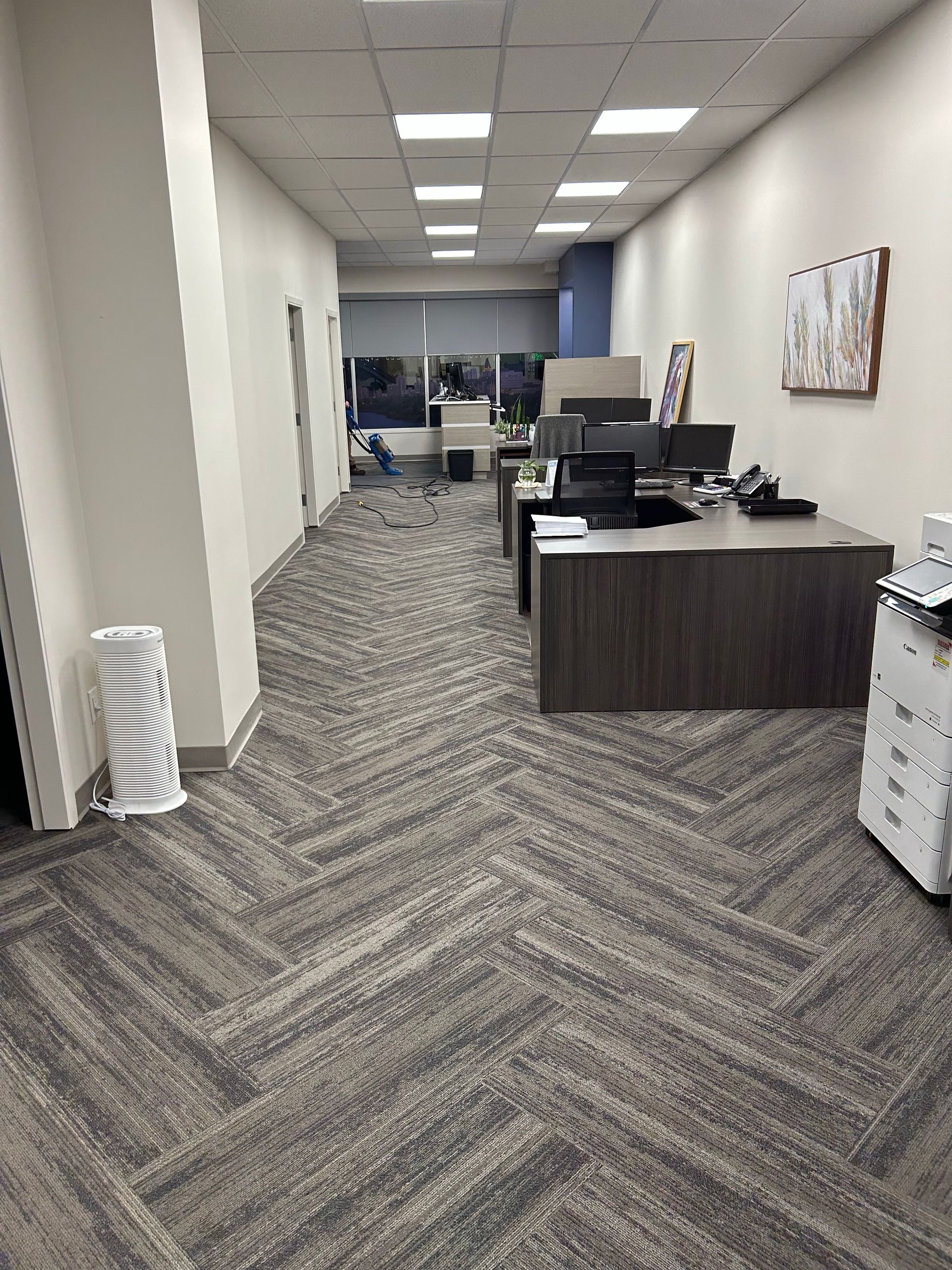 A large office with a herringbone floor and desks.